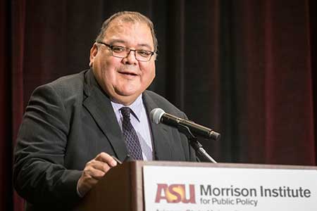  Joe Garcia speaks at a lectern at the State of Our State conference