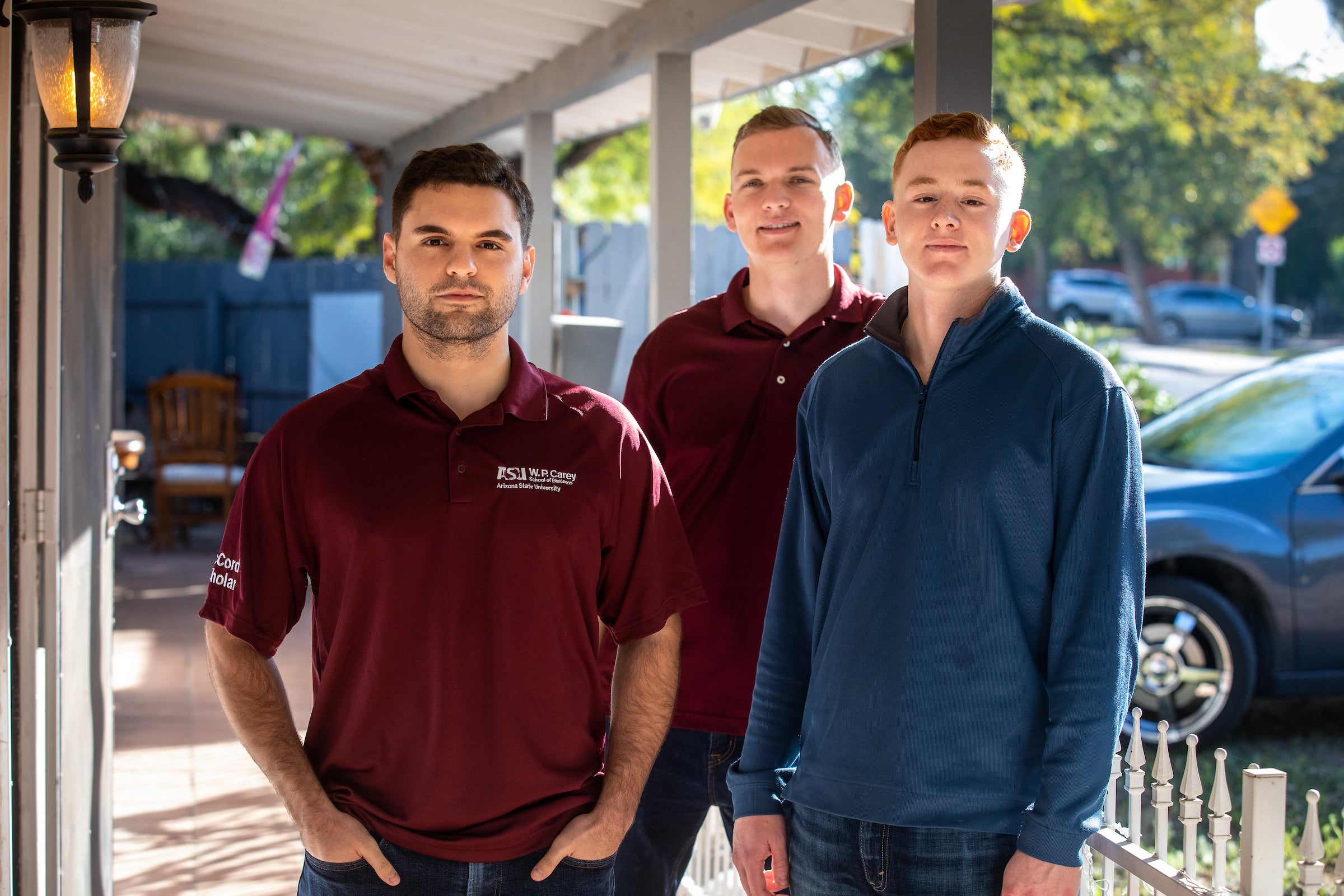 three students posing together in front of apartment for portrait