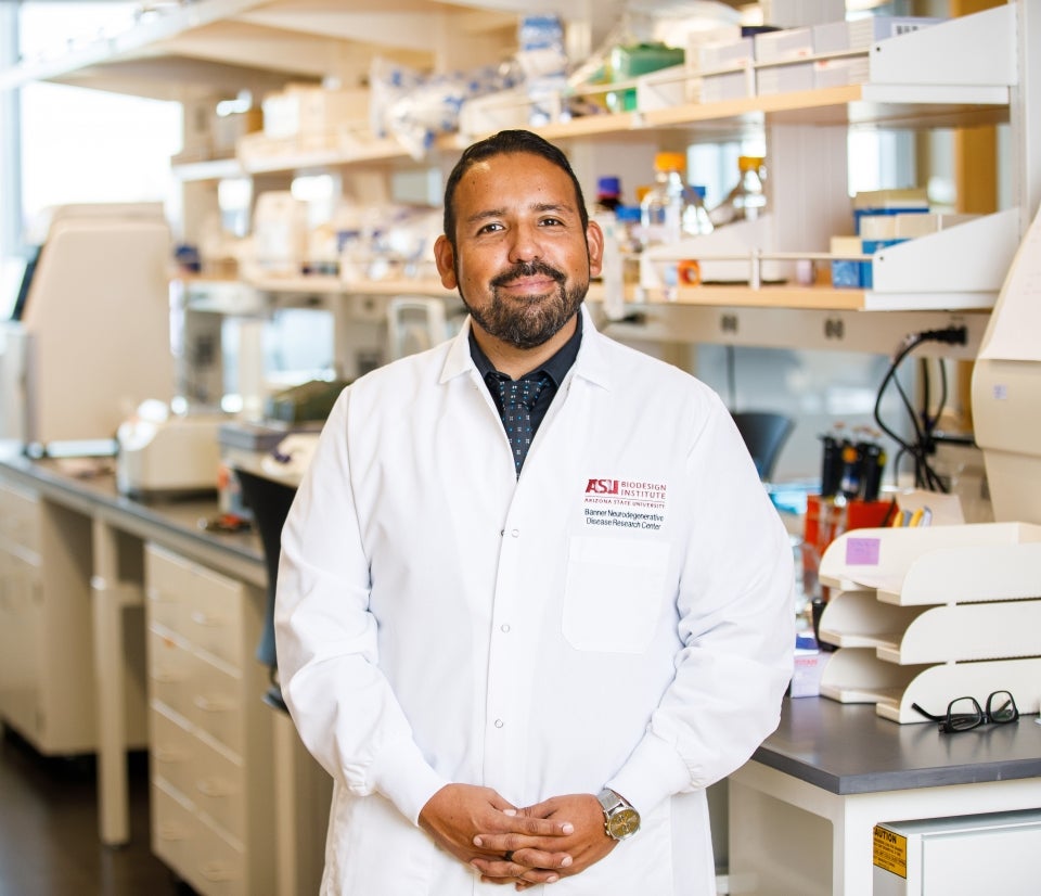 ASU Assistant Professor  wearing a white coat in a lab setting.