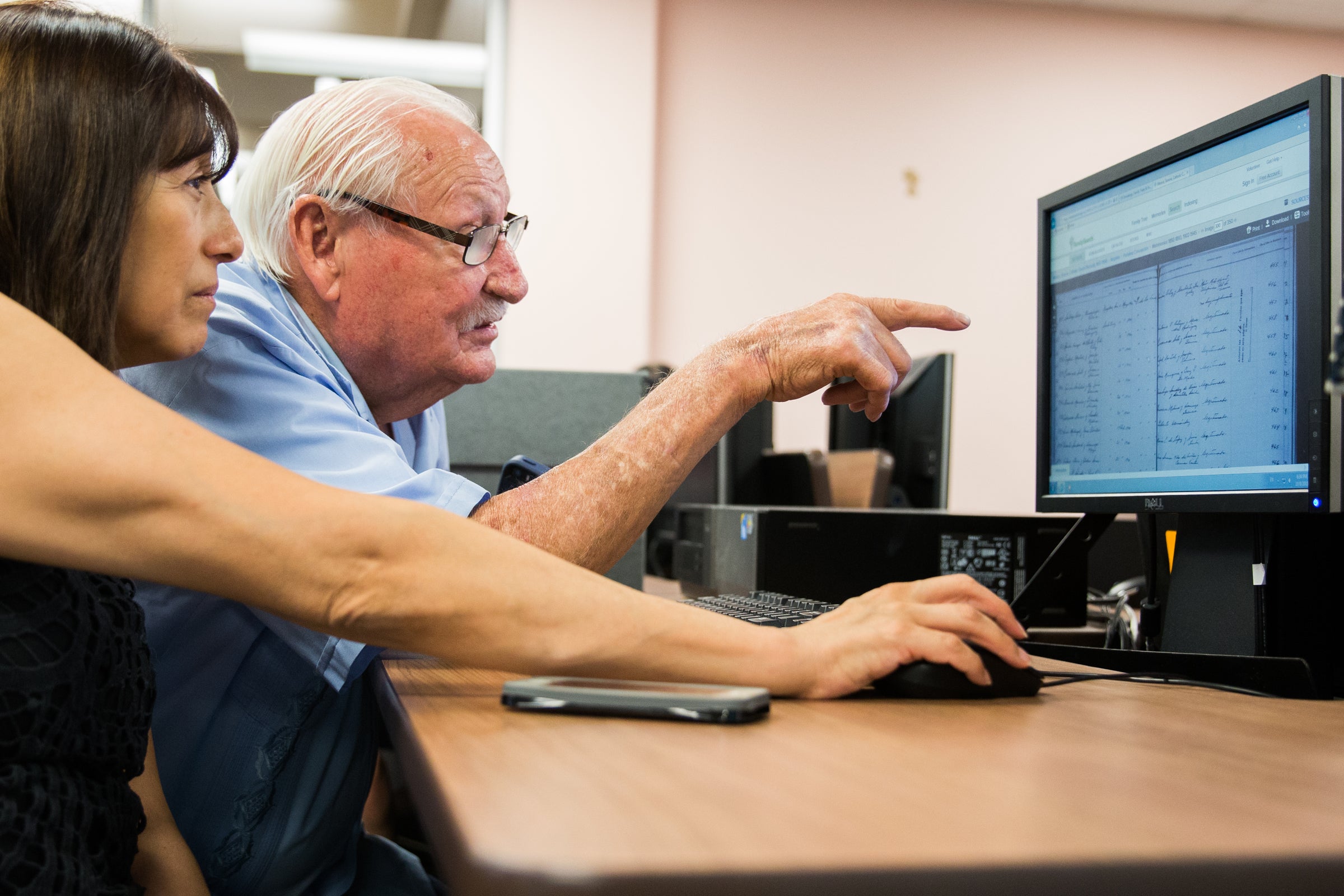 Father and adult daughter look at a computer screen