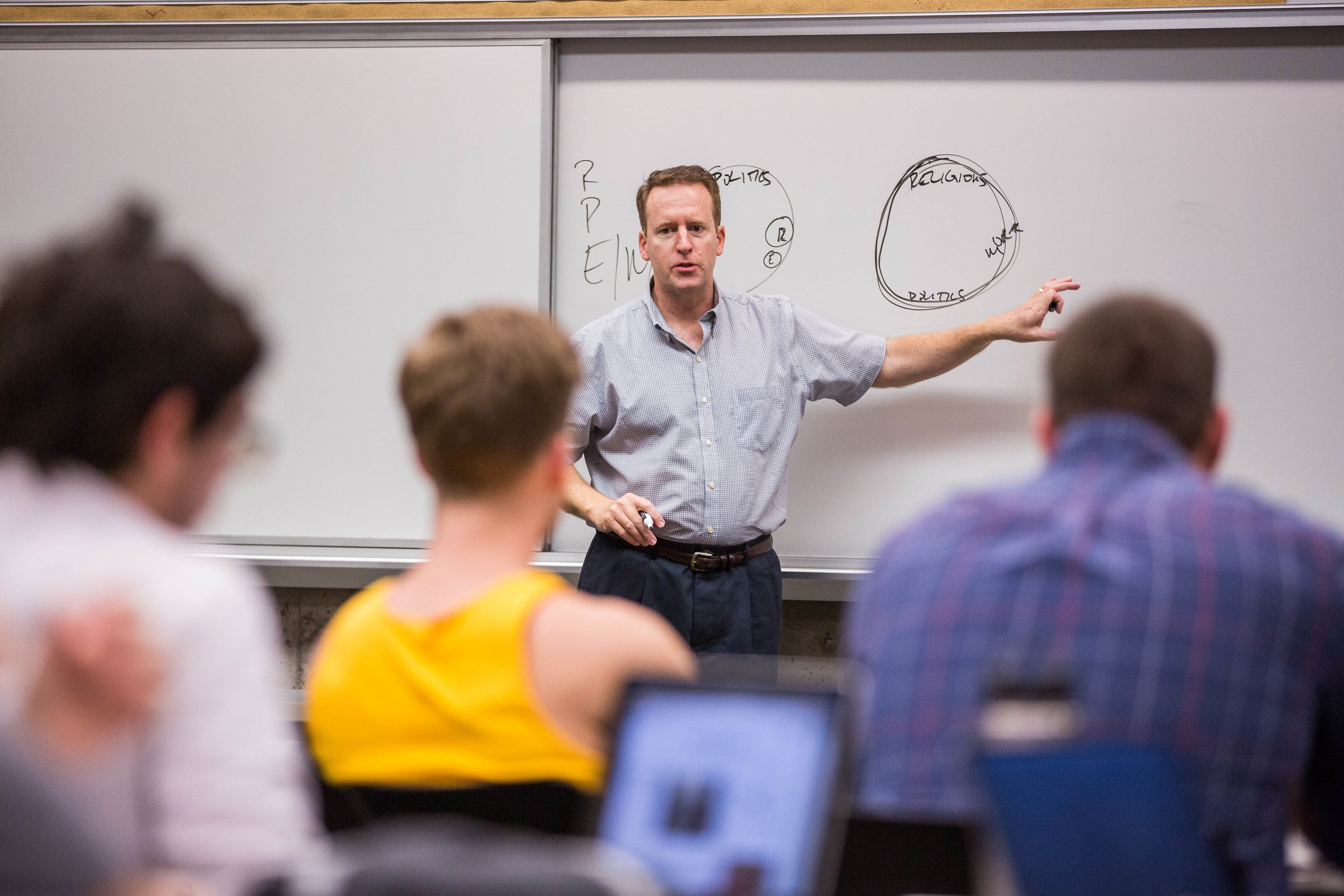 man teaching class pointing to whiteboard