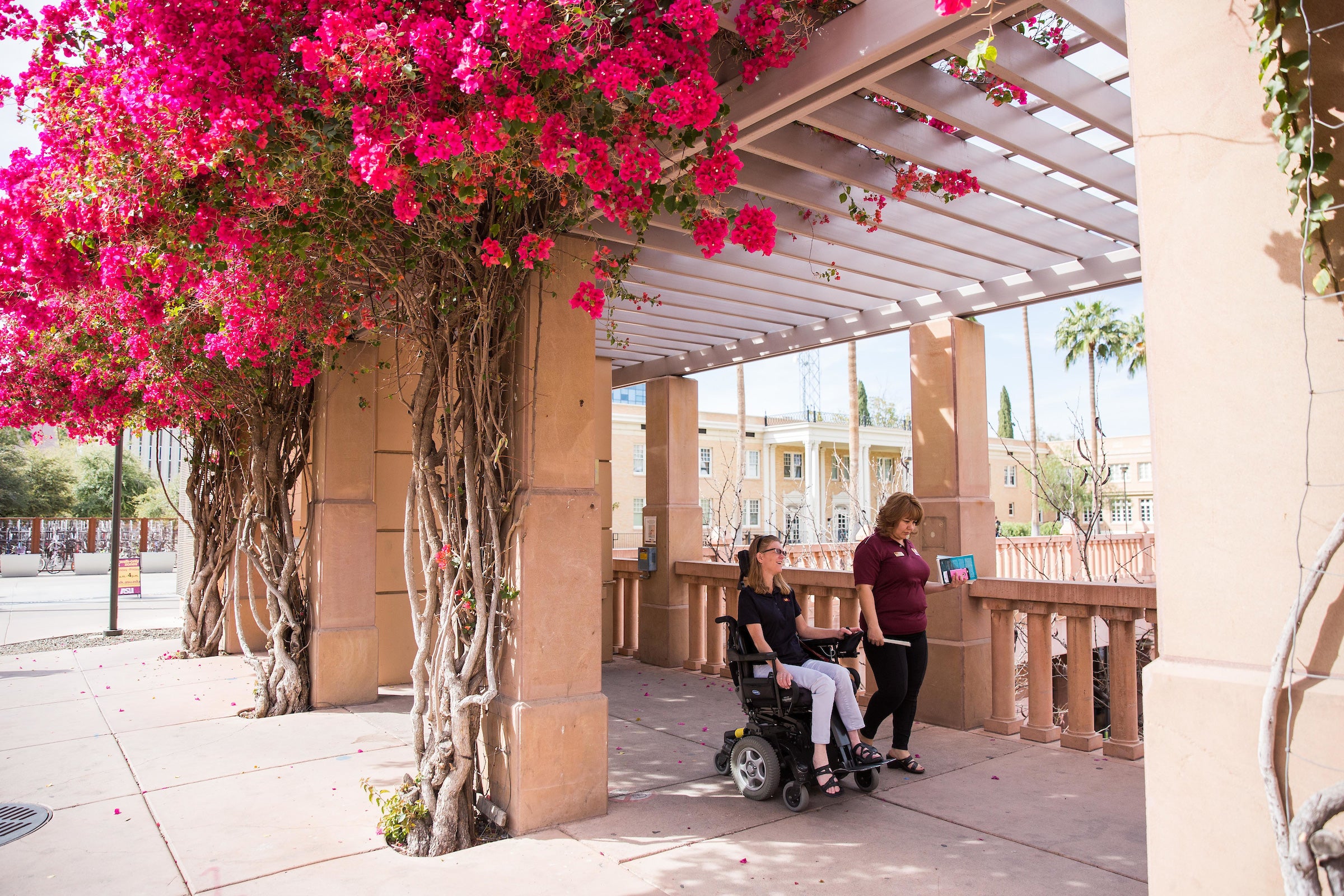 woman walking next to woman riding in wheelchair