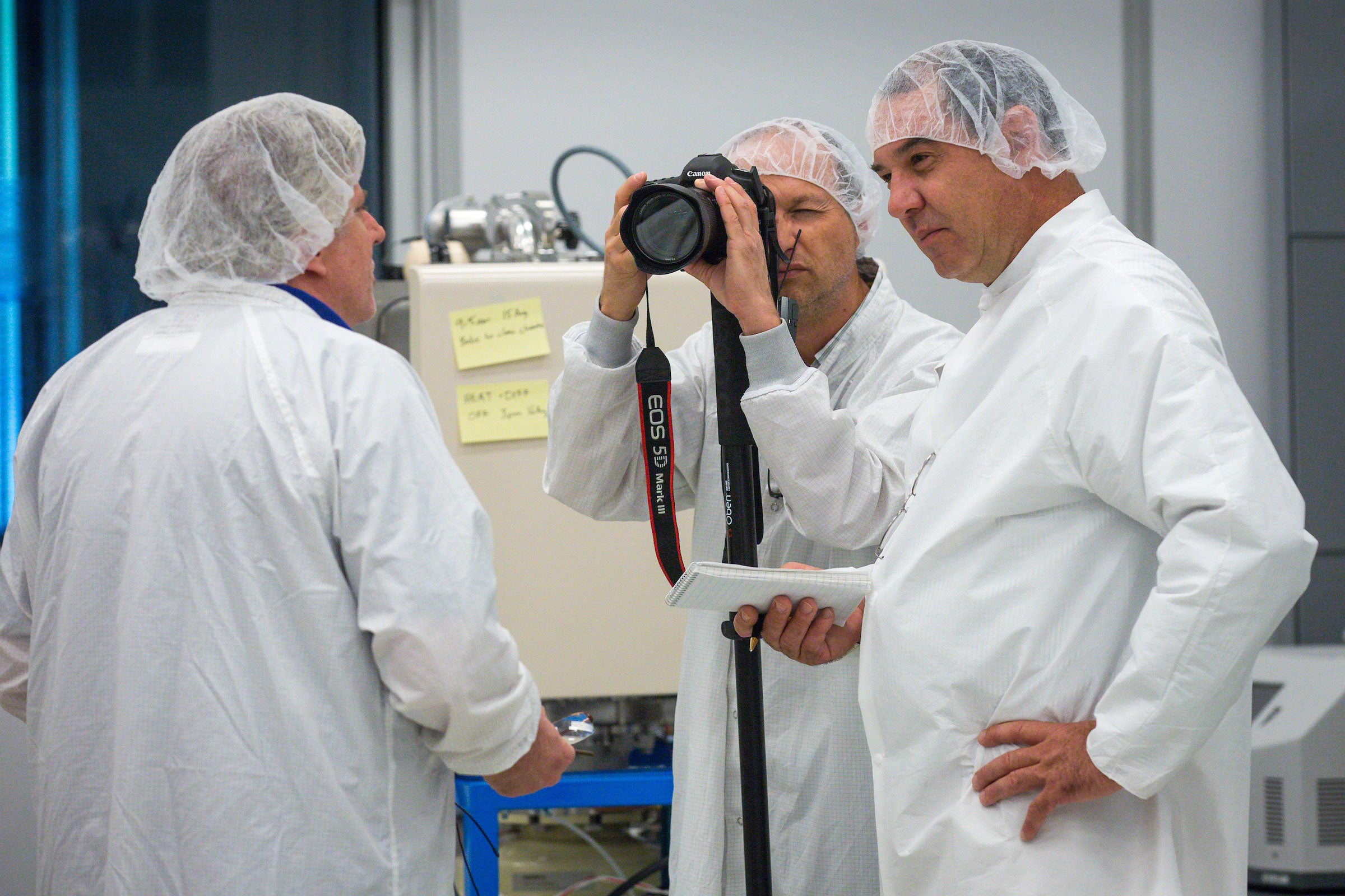 Men in lab coats and hair next speak in a lab