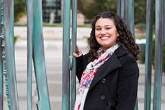 student standing in front of West campus gates