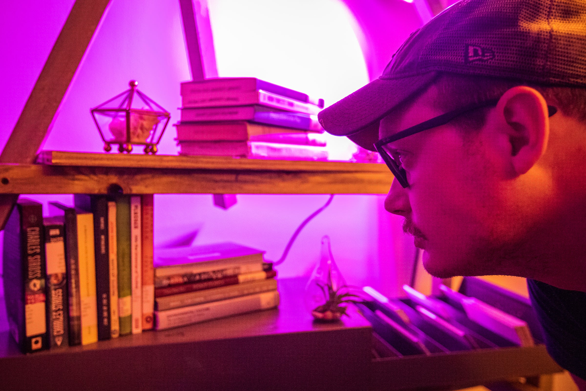 man reading the titles of a stack of books