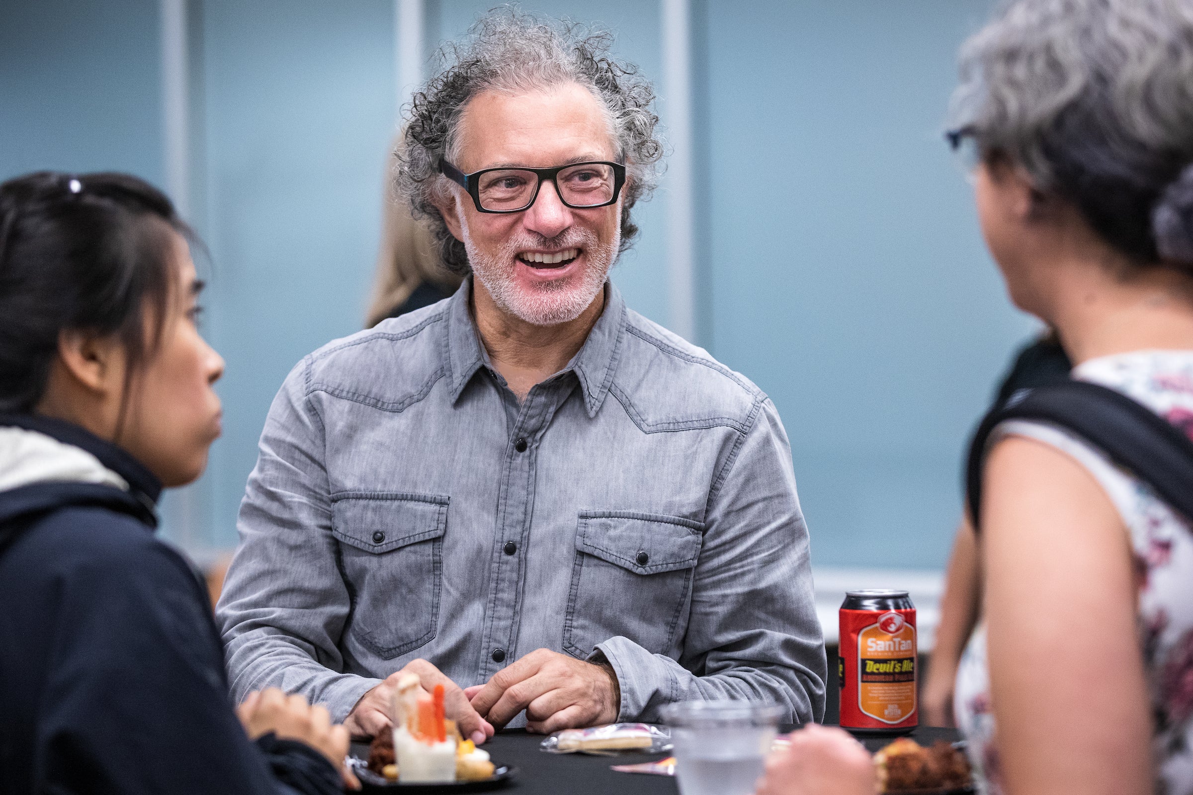 man smiling and talking to people at a cocktail party