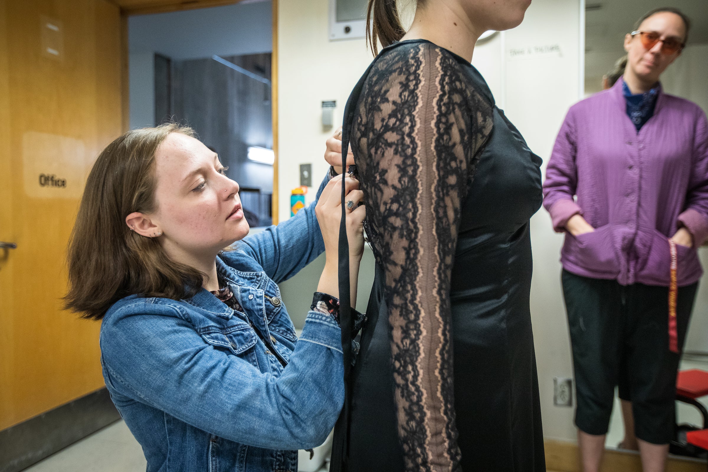 women kneeling to tailor dress worn by other woman