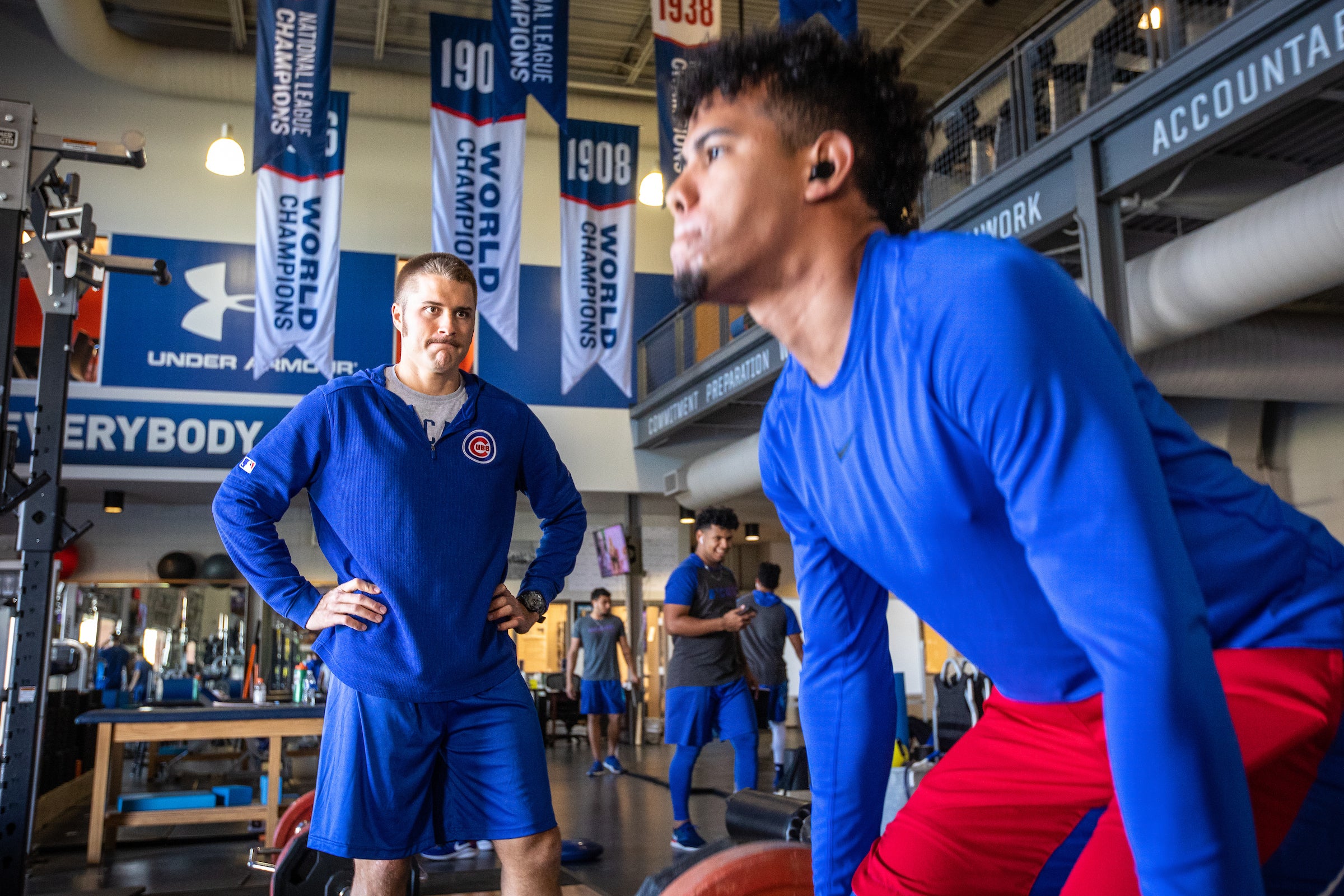 man deadlifting as trainer looks on