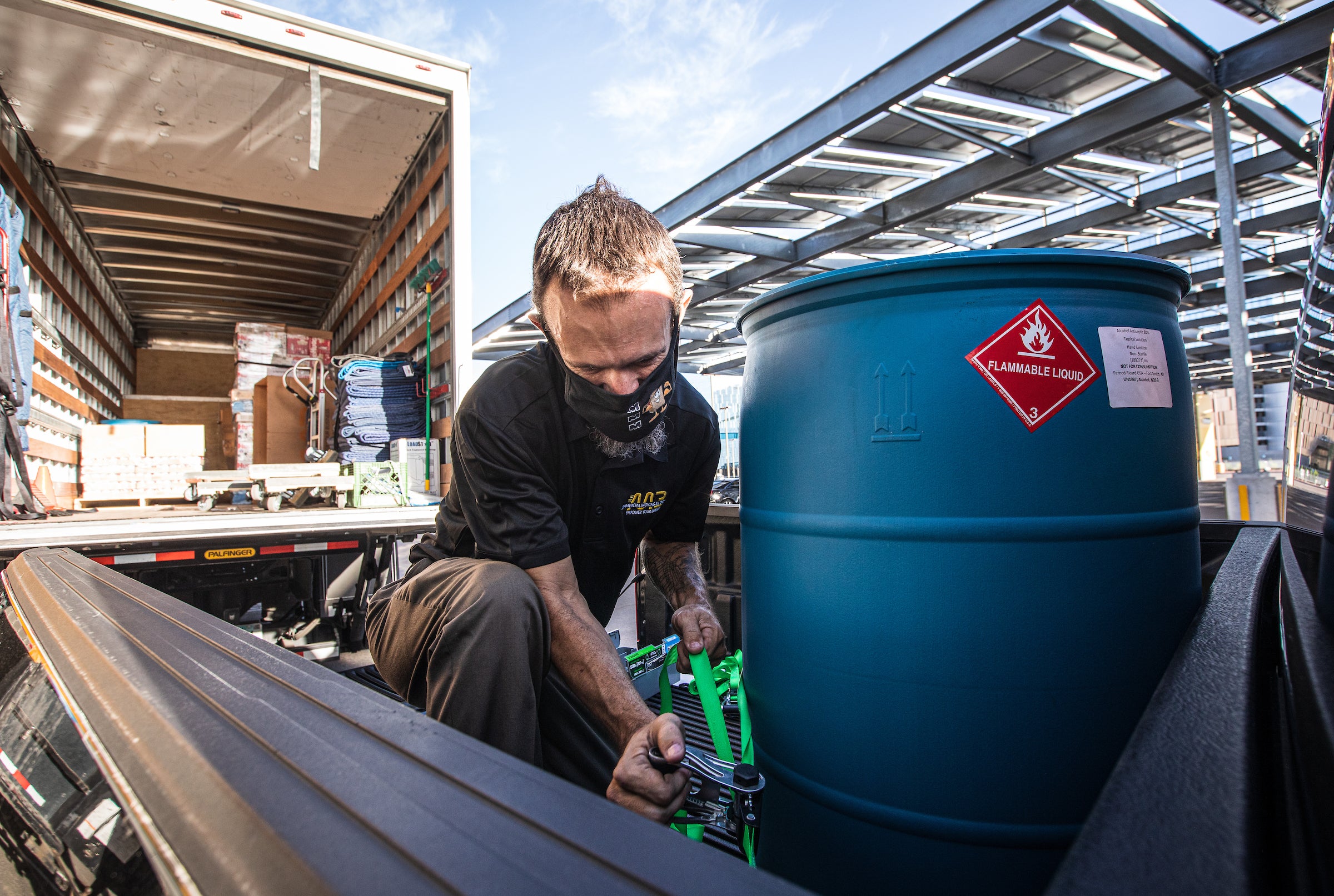 Worker loads a vat of hand sanitizer onto a truck 