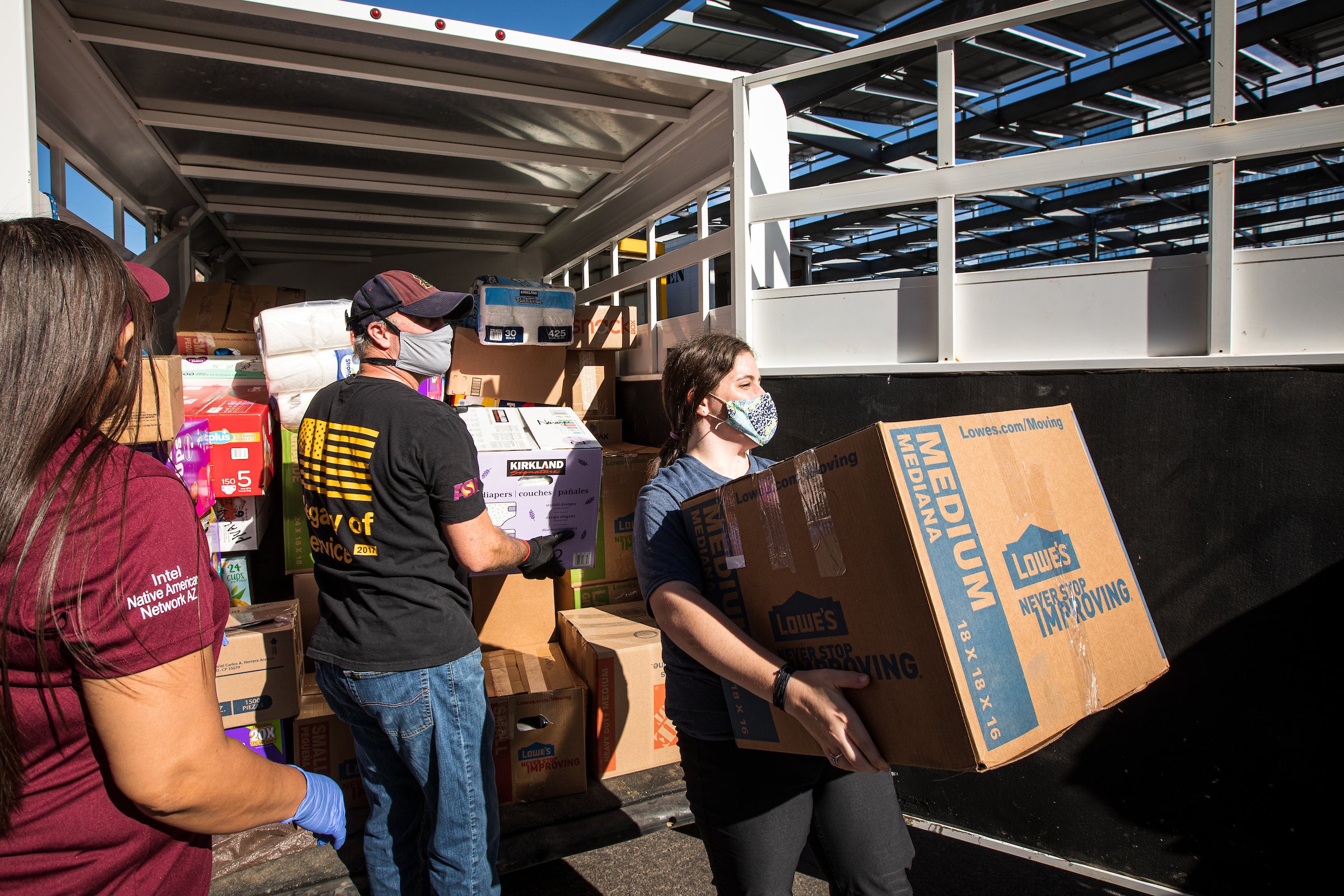 Girl carries a box of donations from a loaded trailer