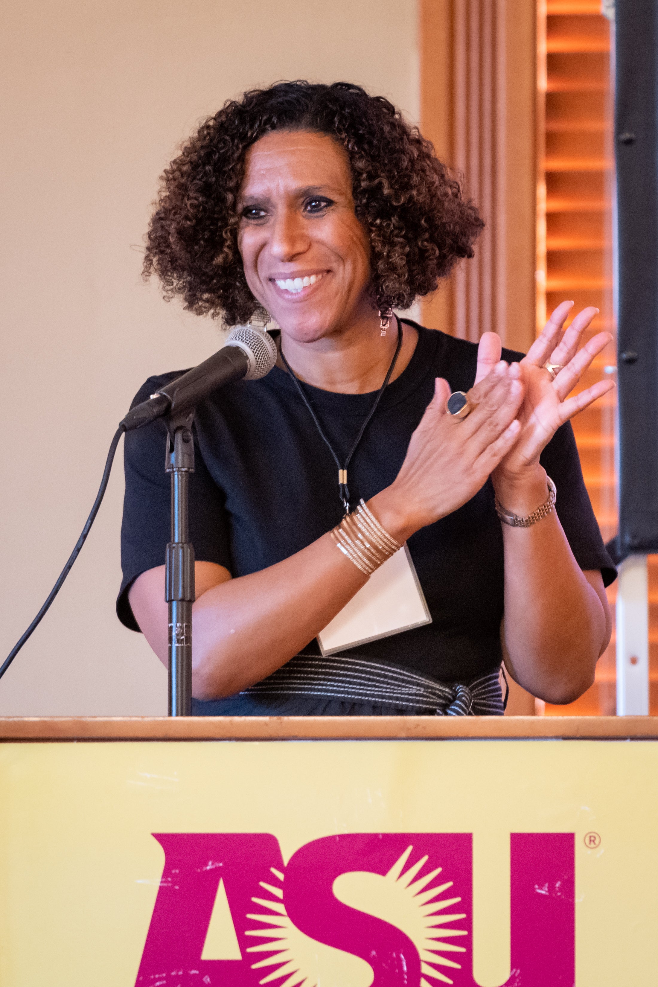 woman standing behind a lectern, clapping