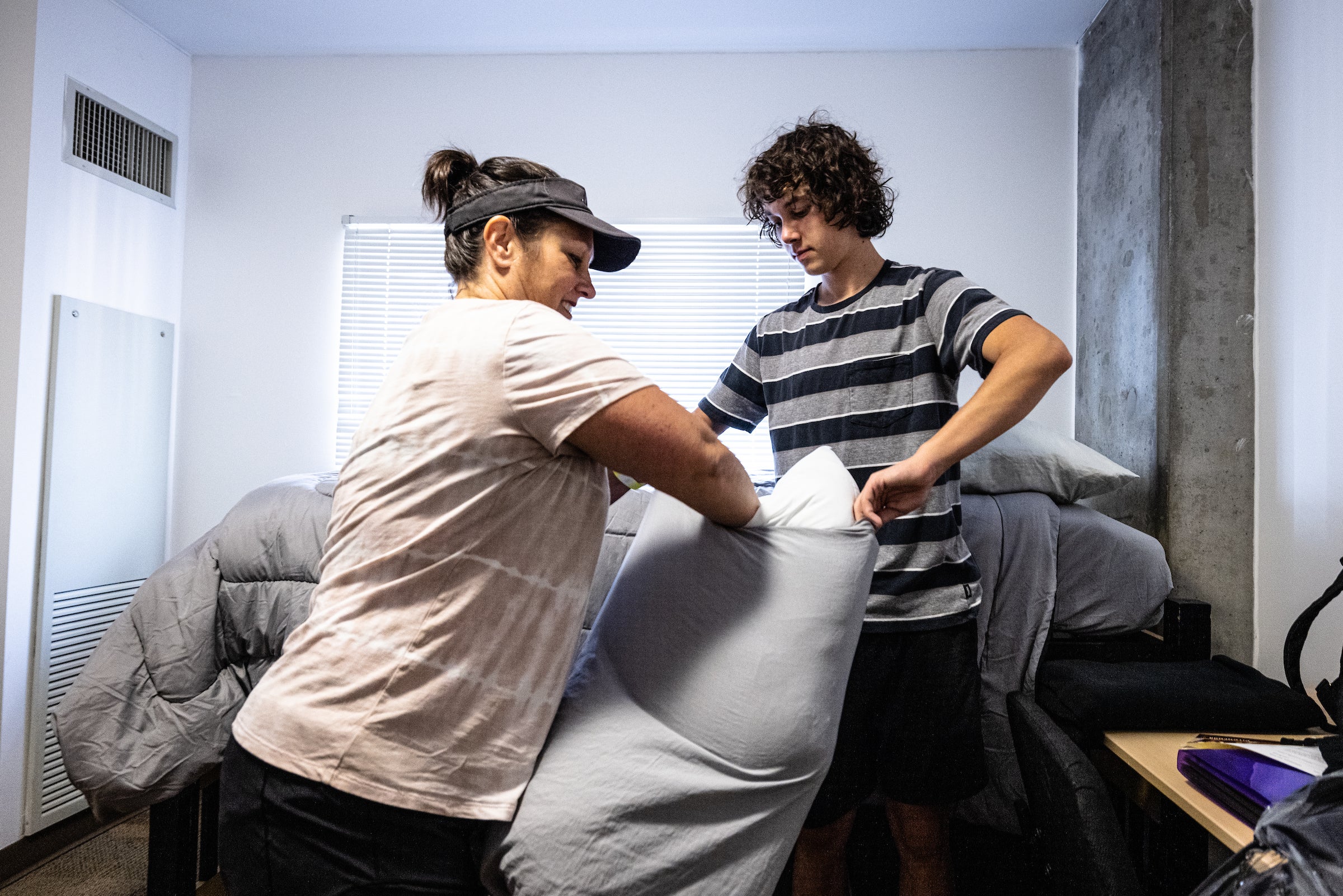 mother and son making dorm room bed