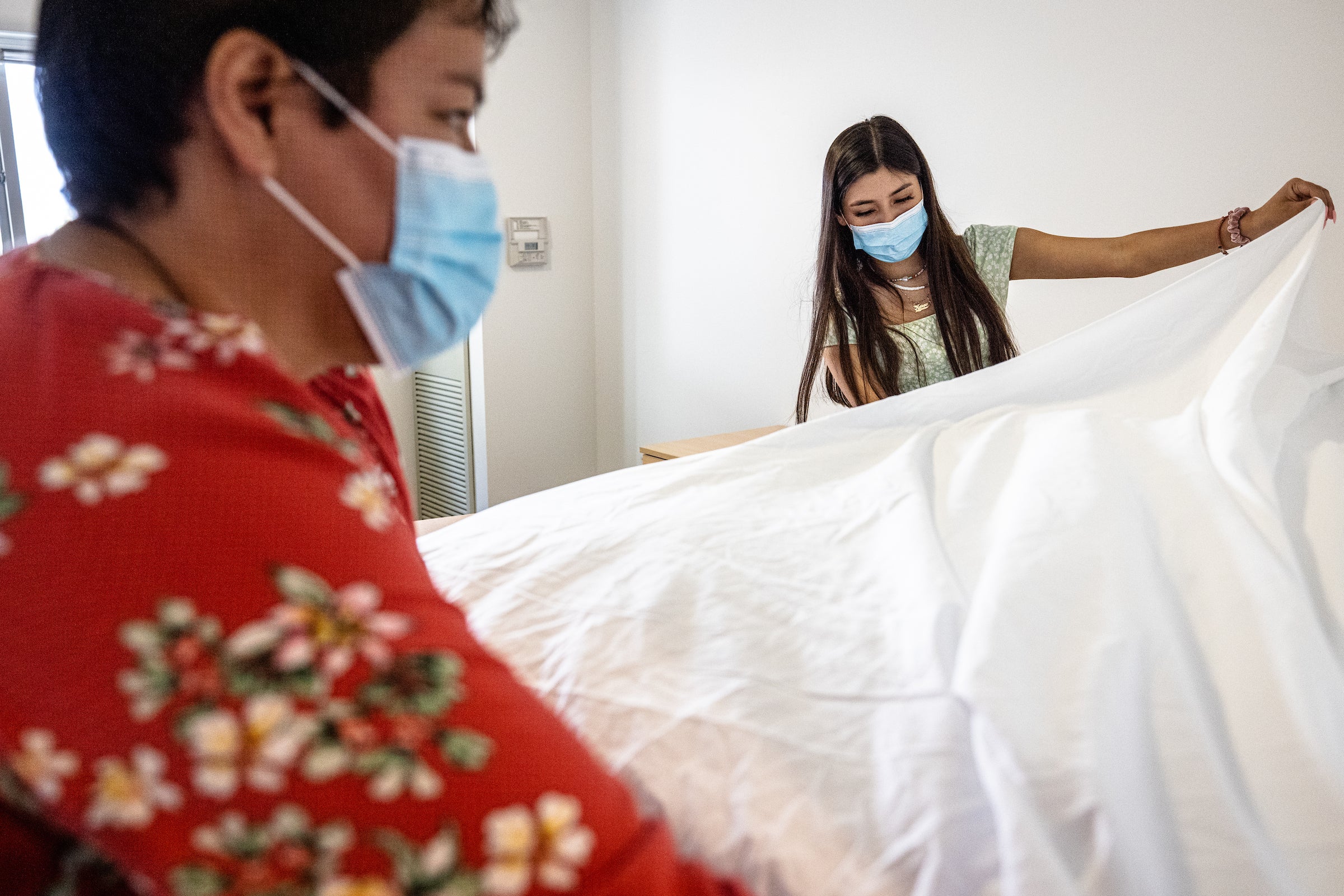 mother and daughter make the bed in her new dorm room