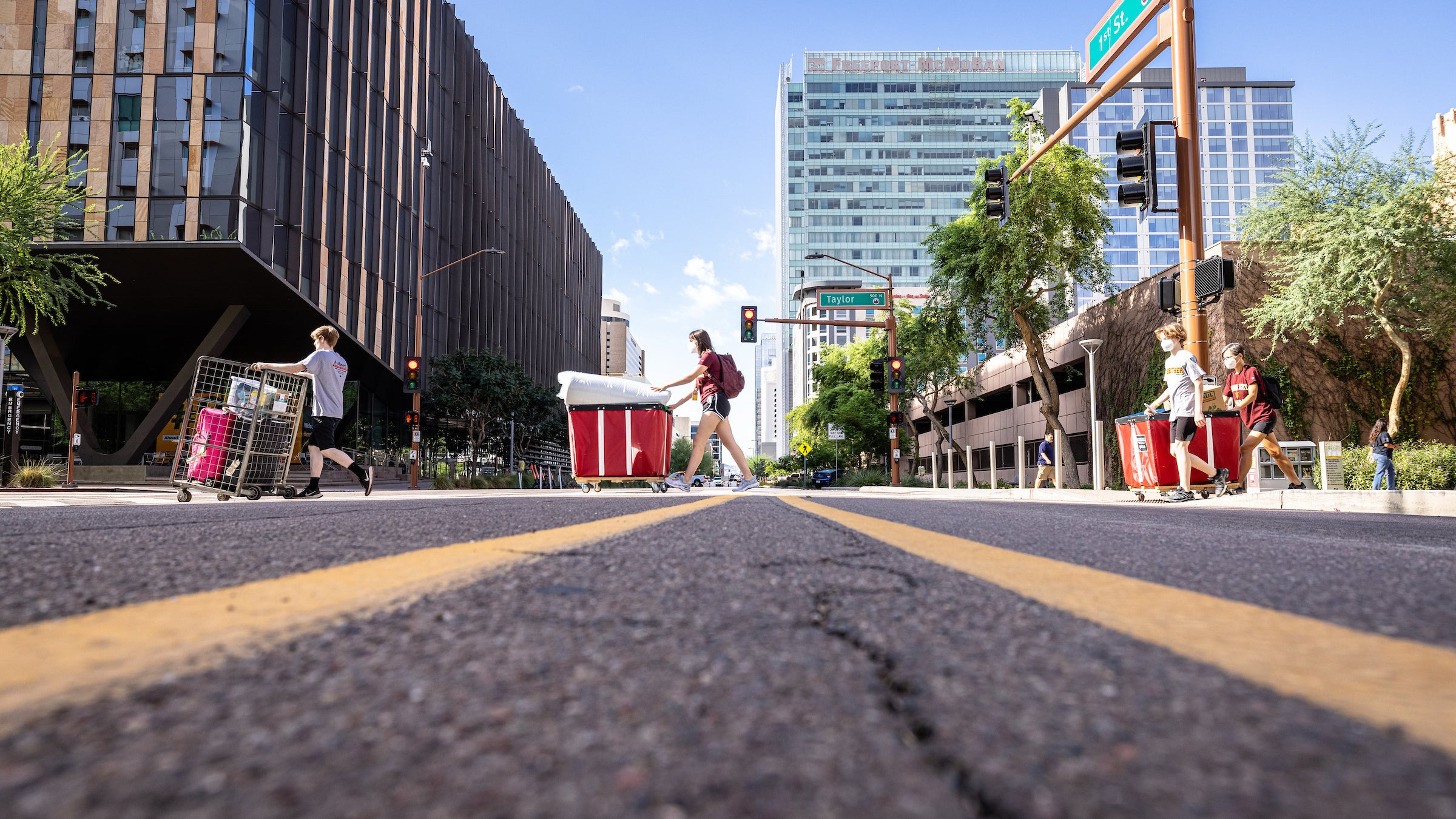 Students move big carts of belongings across a downtown street