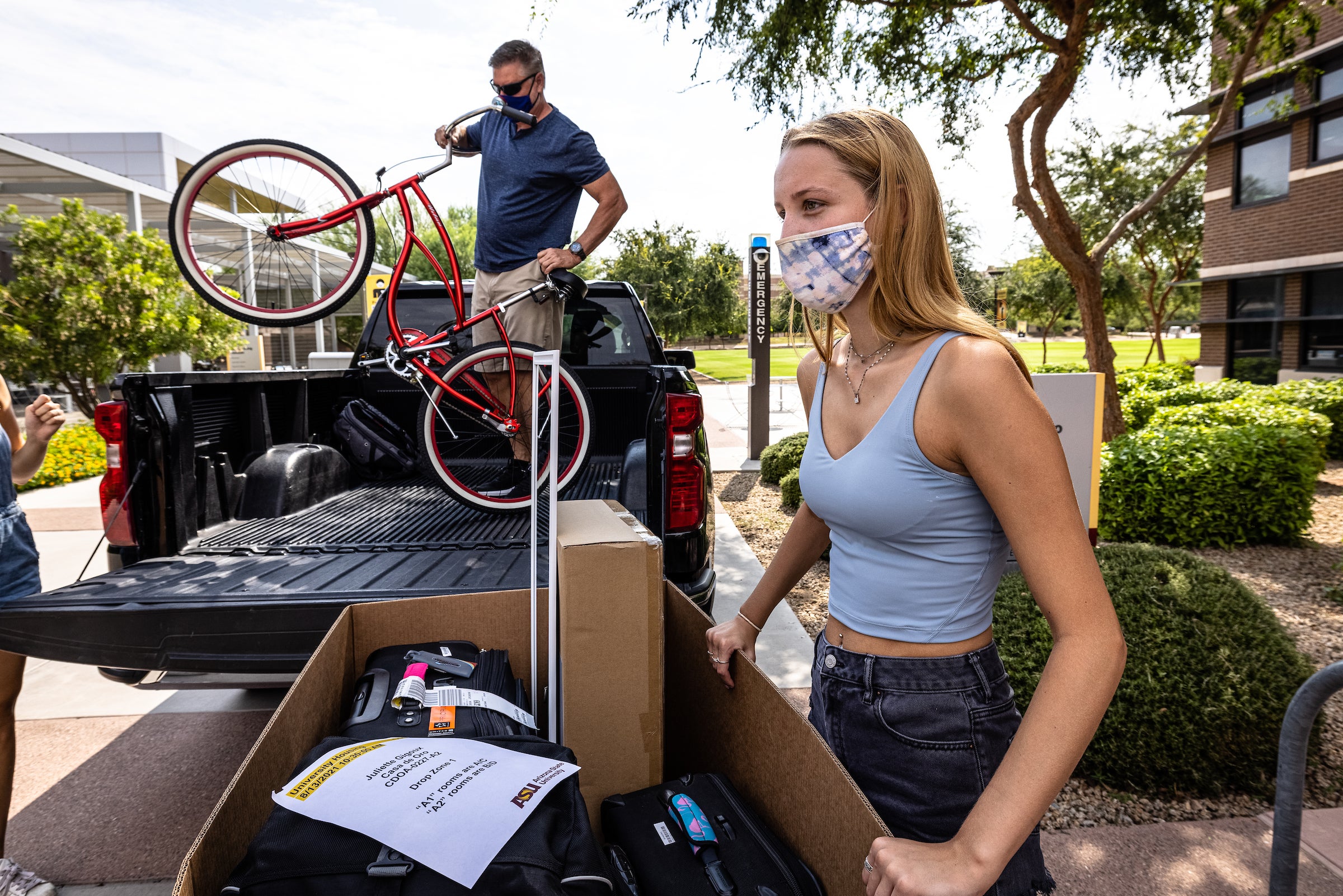 dad helping daughter unload bicycle from car