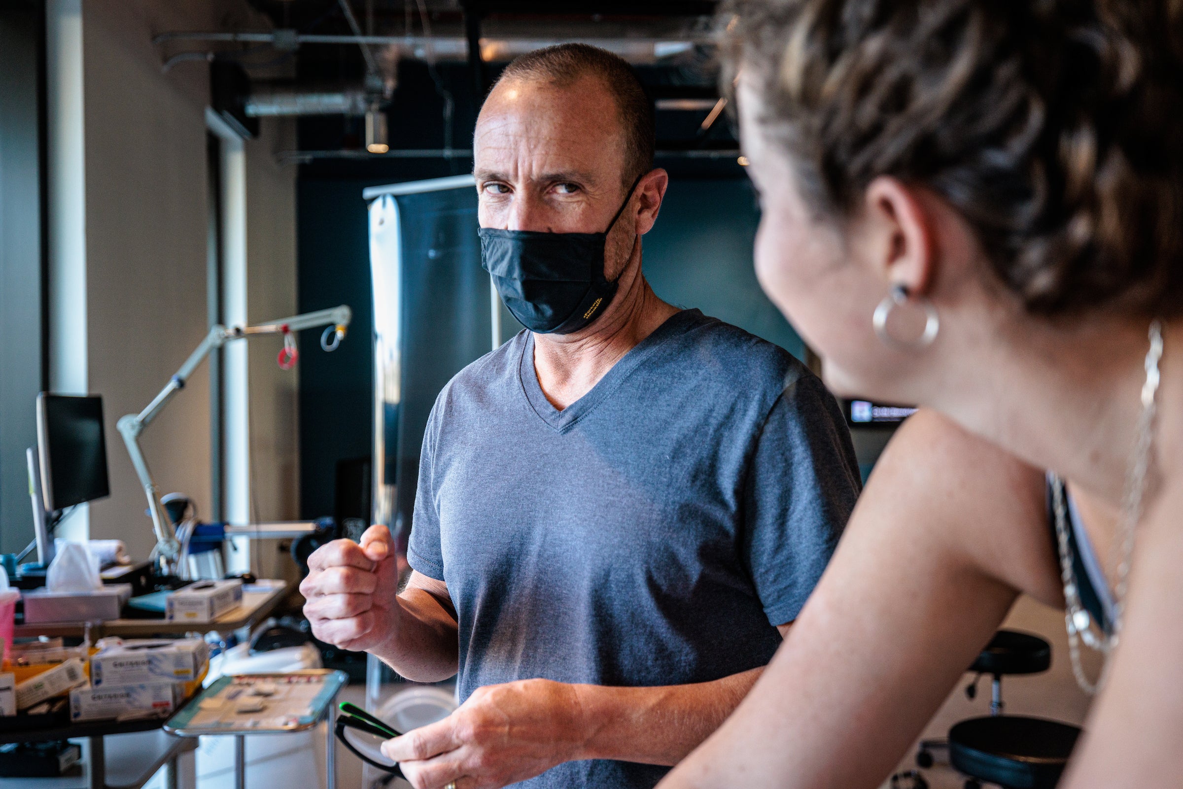 A man holds his hand in a fist as he encourages a woman on a stationary cycle to keep going