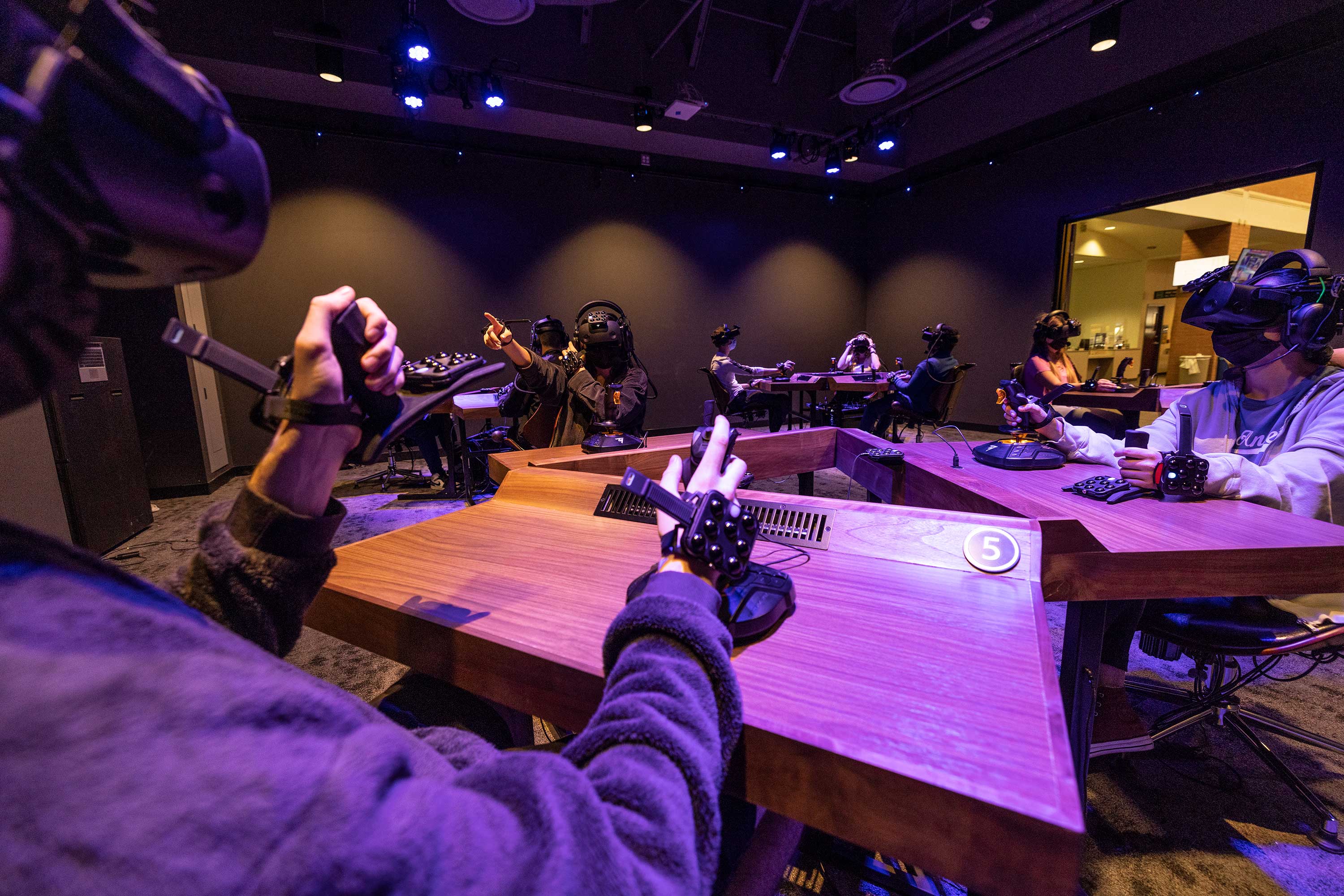 Group of students in classroom using VR headsets and joysticks