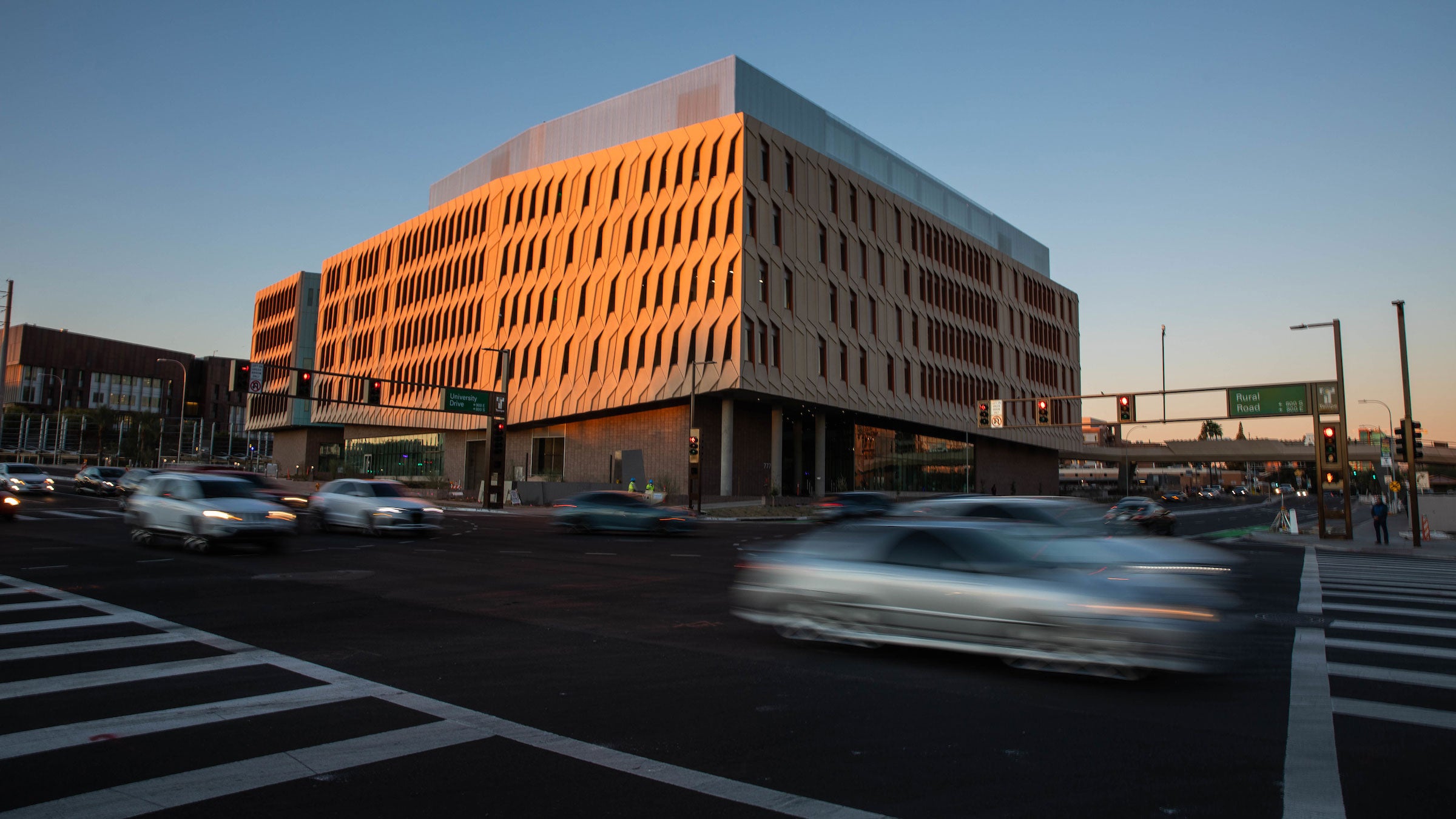 Blurred cars pass in front of the ISTB7 building lit by the rising sun 