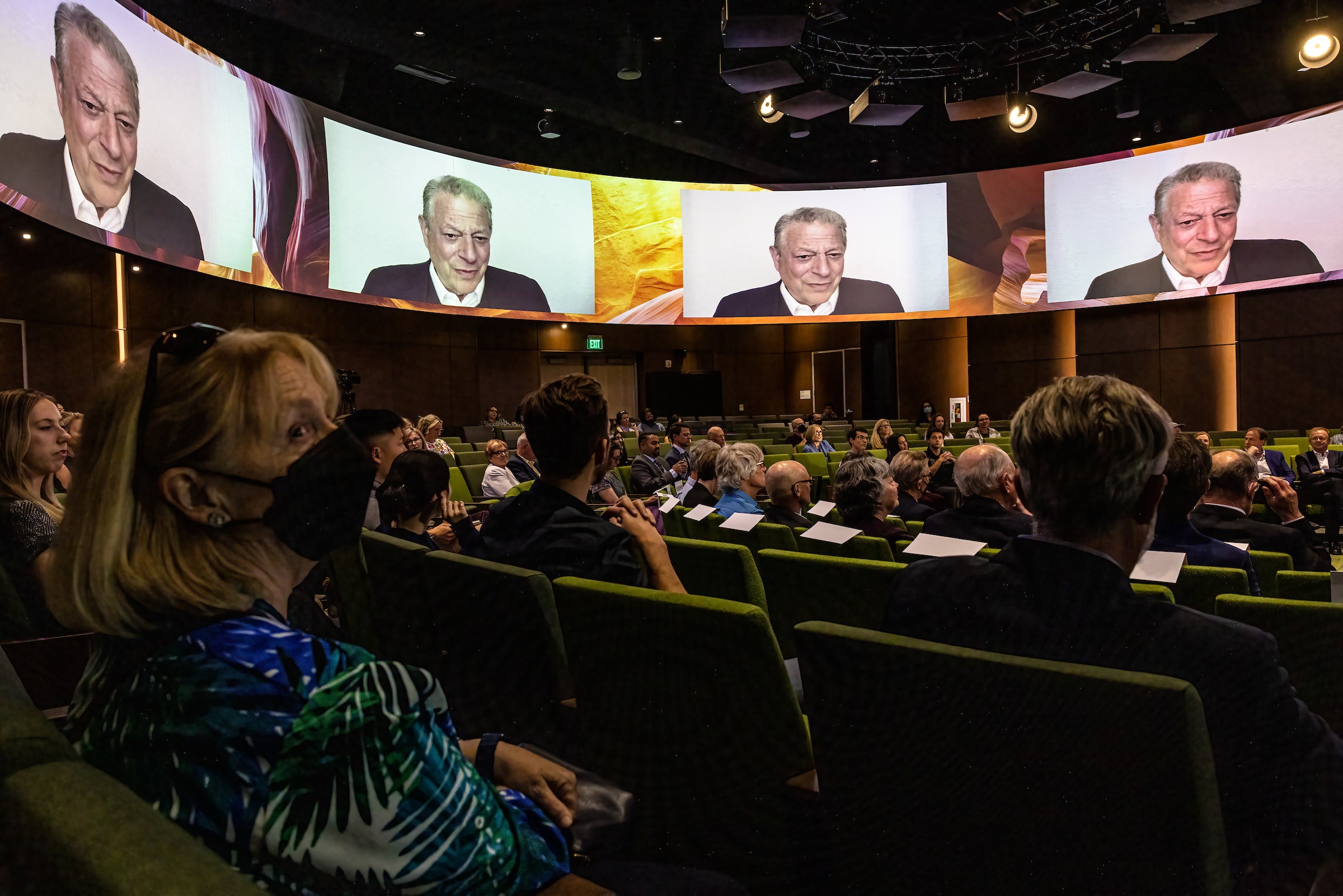 Audience watching Al Gore talk on screens around room