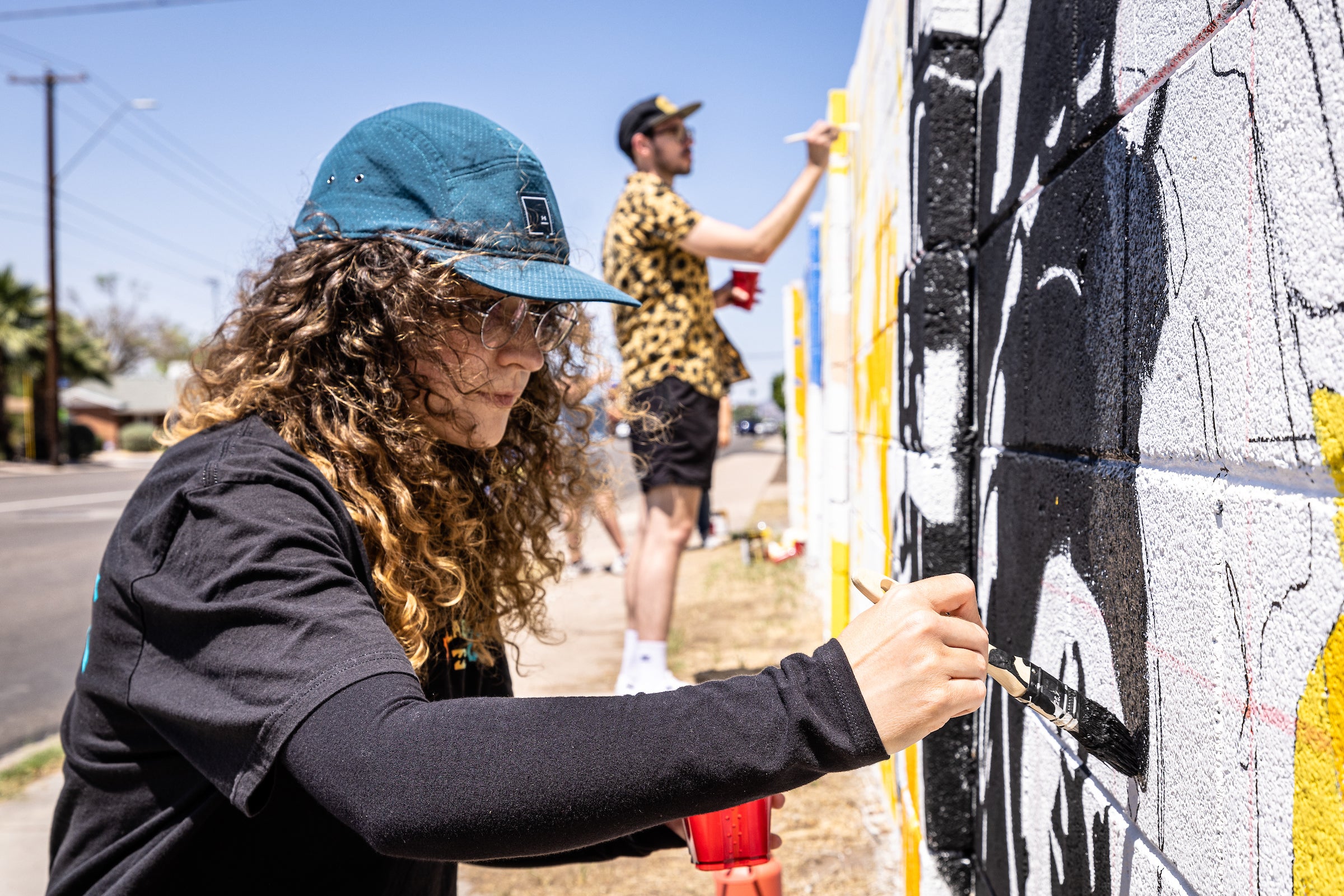 Student painting mural on a wall