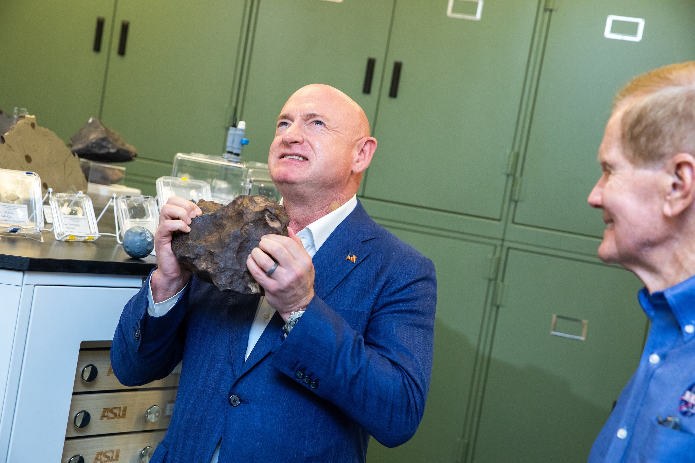 Sen. Mark Kelly grimaces as he lifts a large meteorite