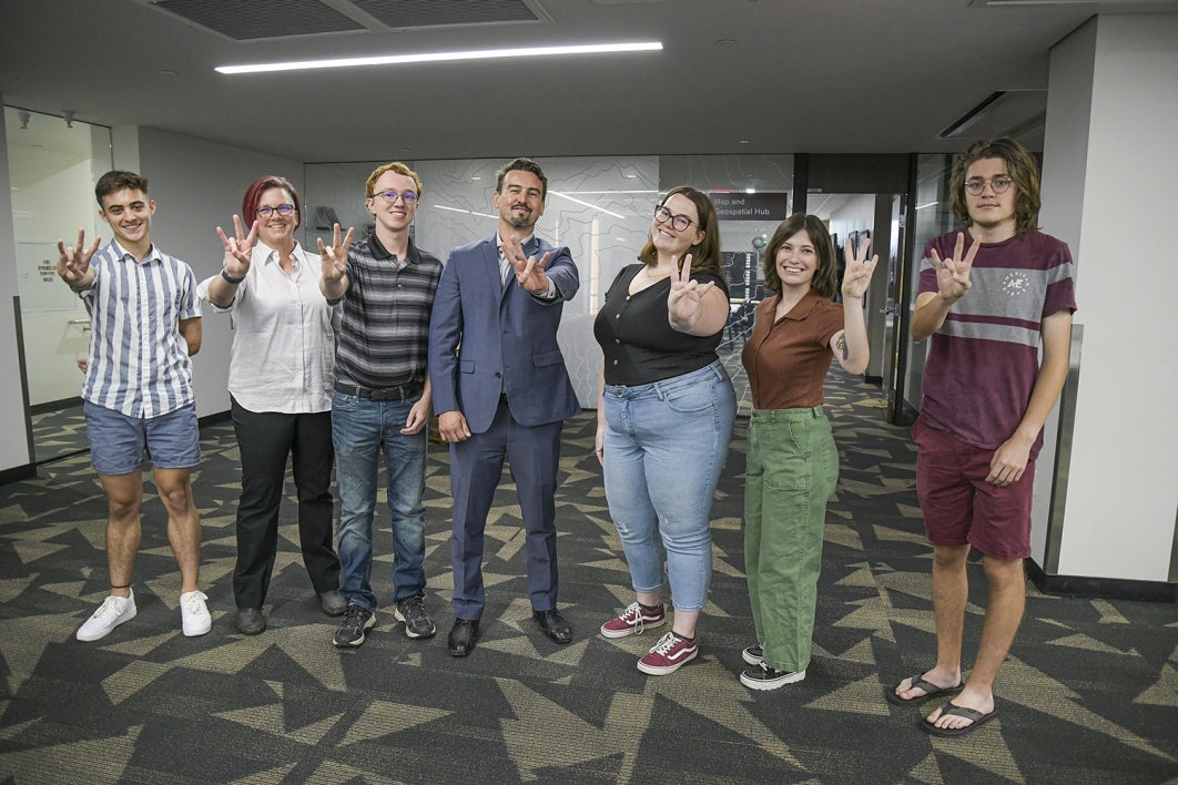 A group of people standing and making the "Forks up" hand sign