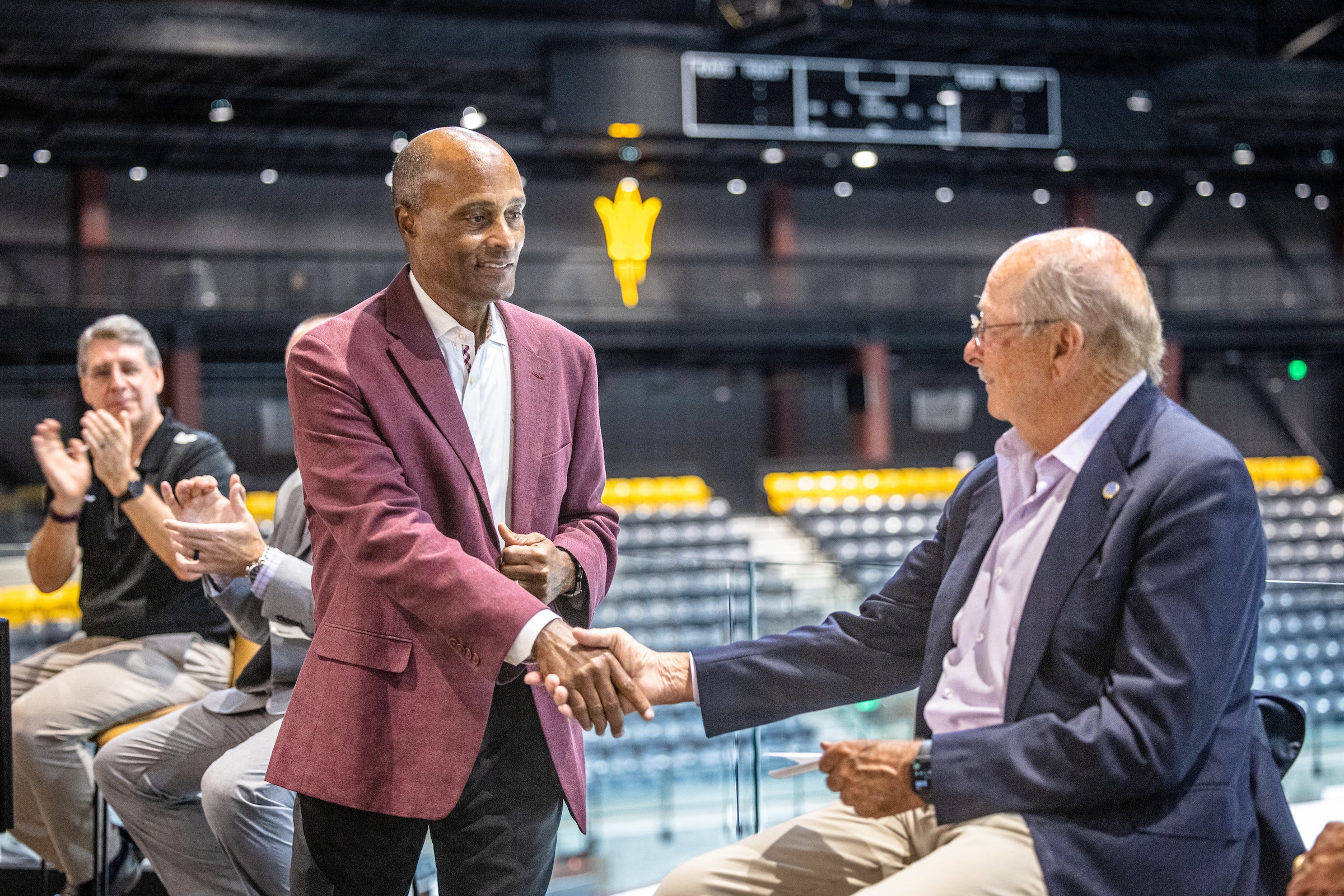 Man shakes hands with another man during naming event at hockey center