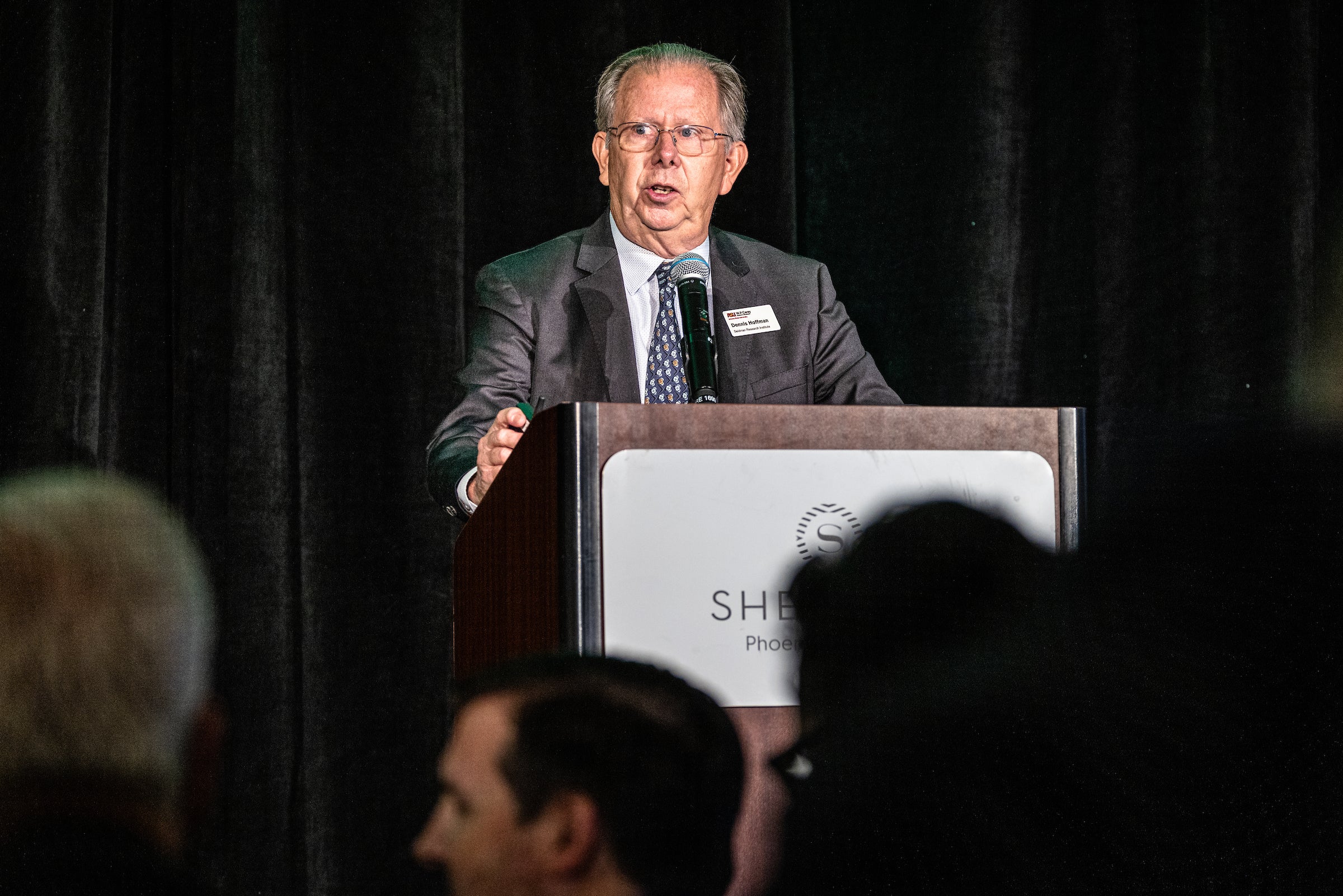 man speaking at lectern in front of audience