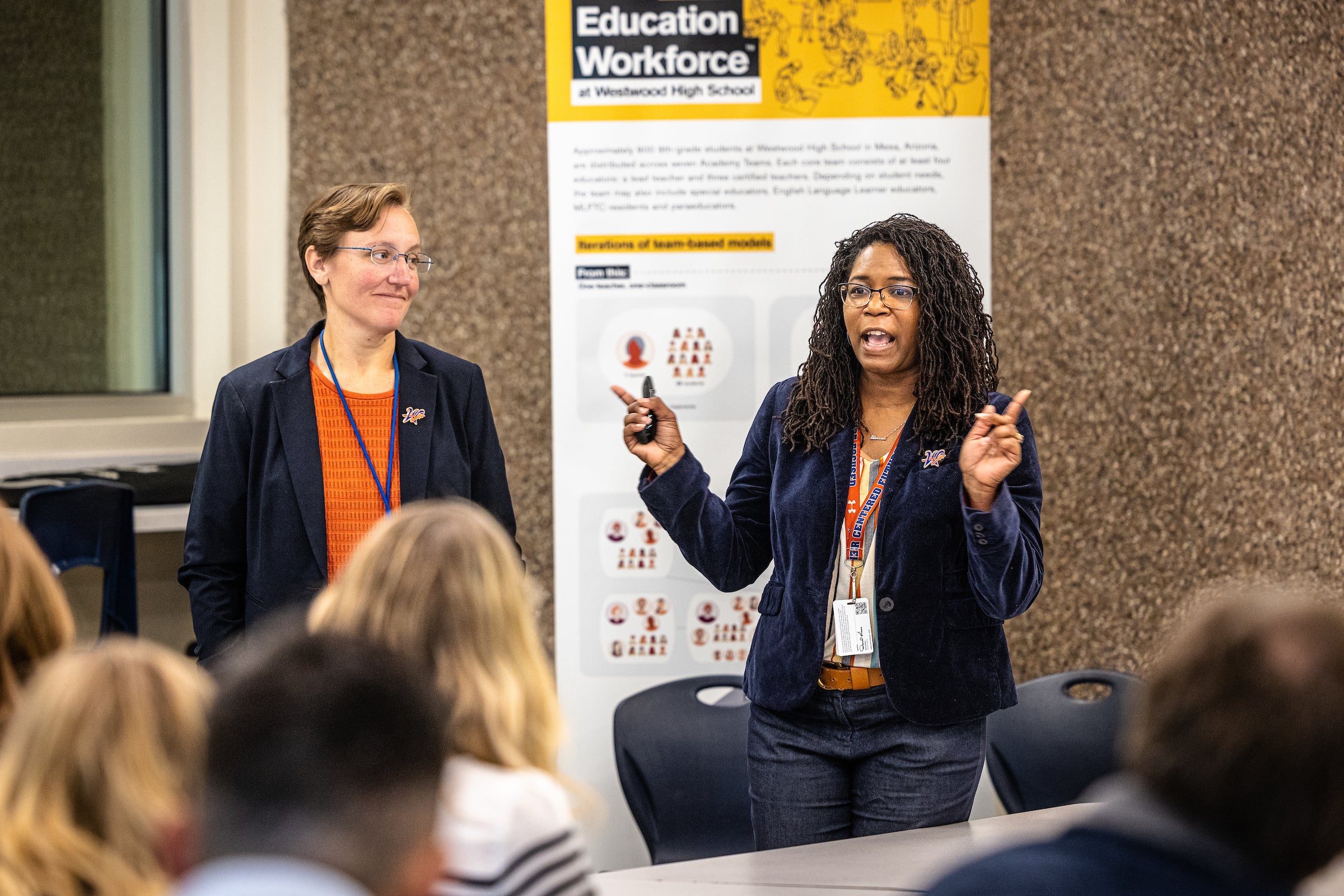 Two women speak to crowd during presentation