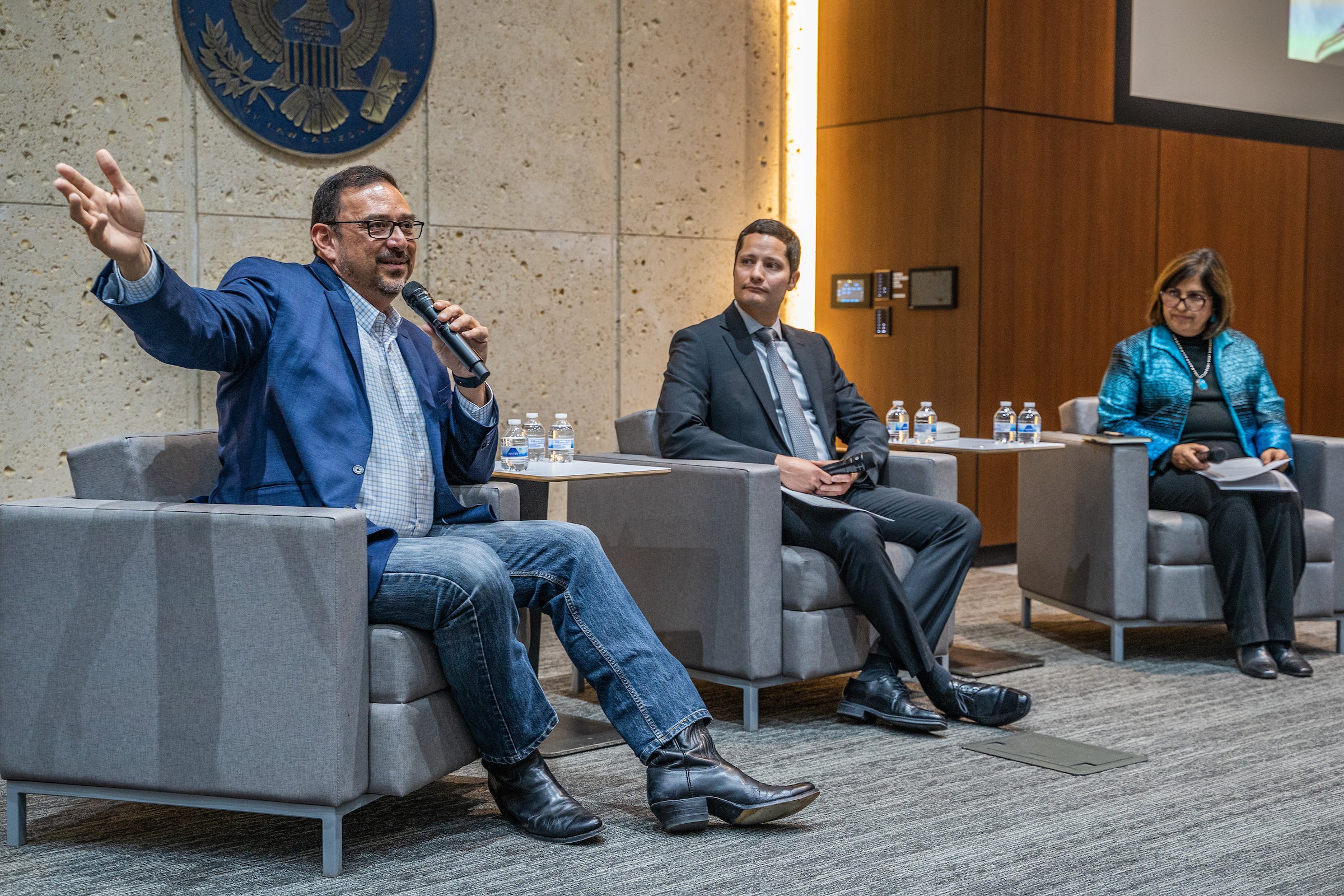 Adrian Fontes speaking at event while two ASU professors sit on stage next to him