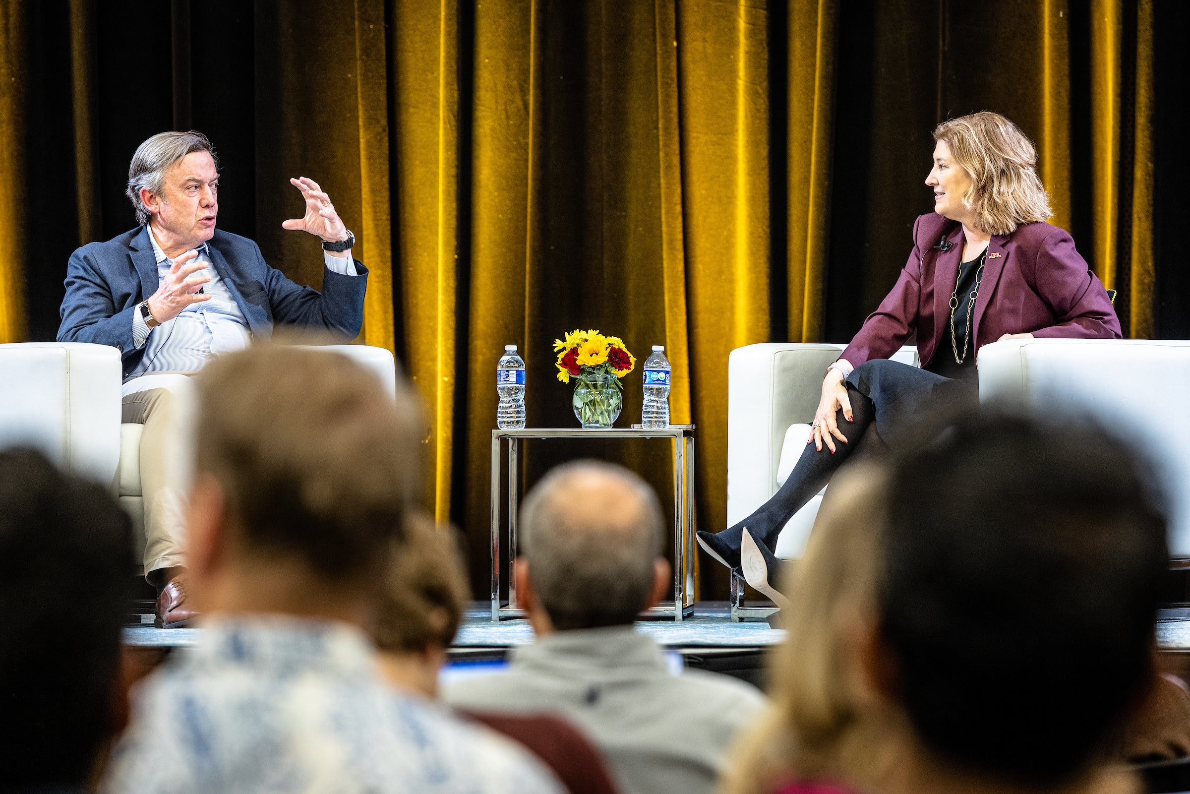 Two people sitting on stage talking in front of audience