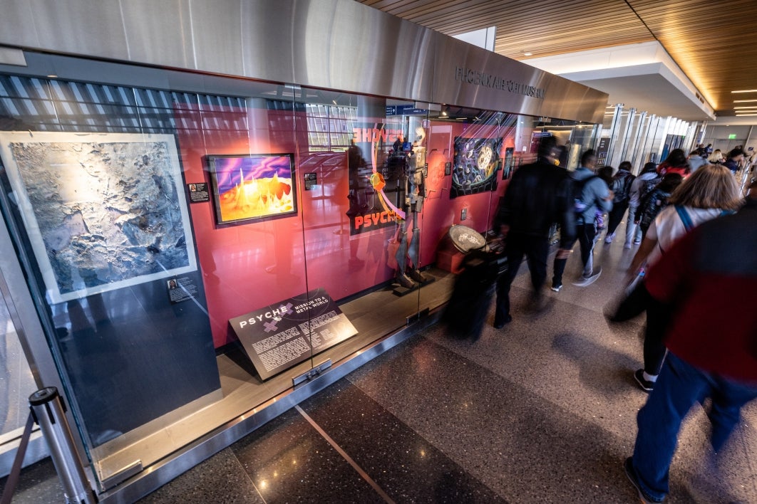 Travelers walking by and looking at an exhibit at an airport