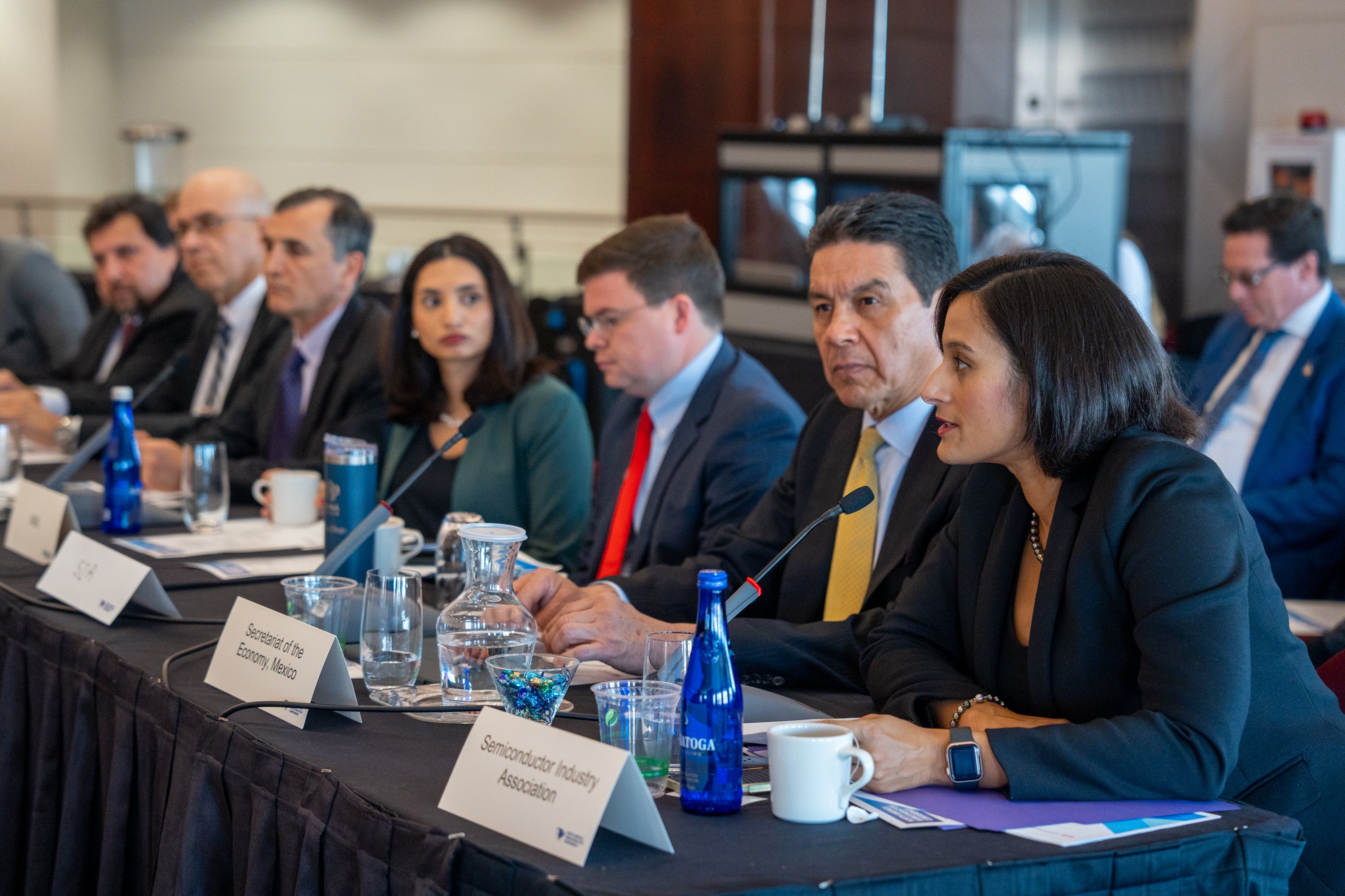 People in suits sitting at a conference table speak