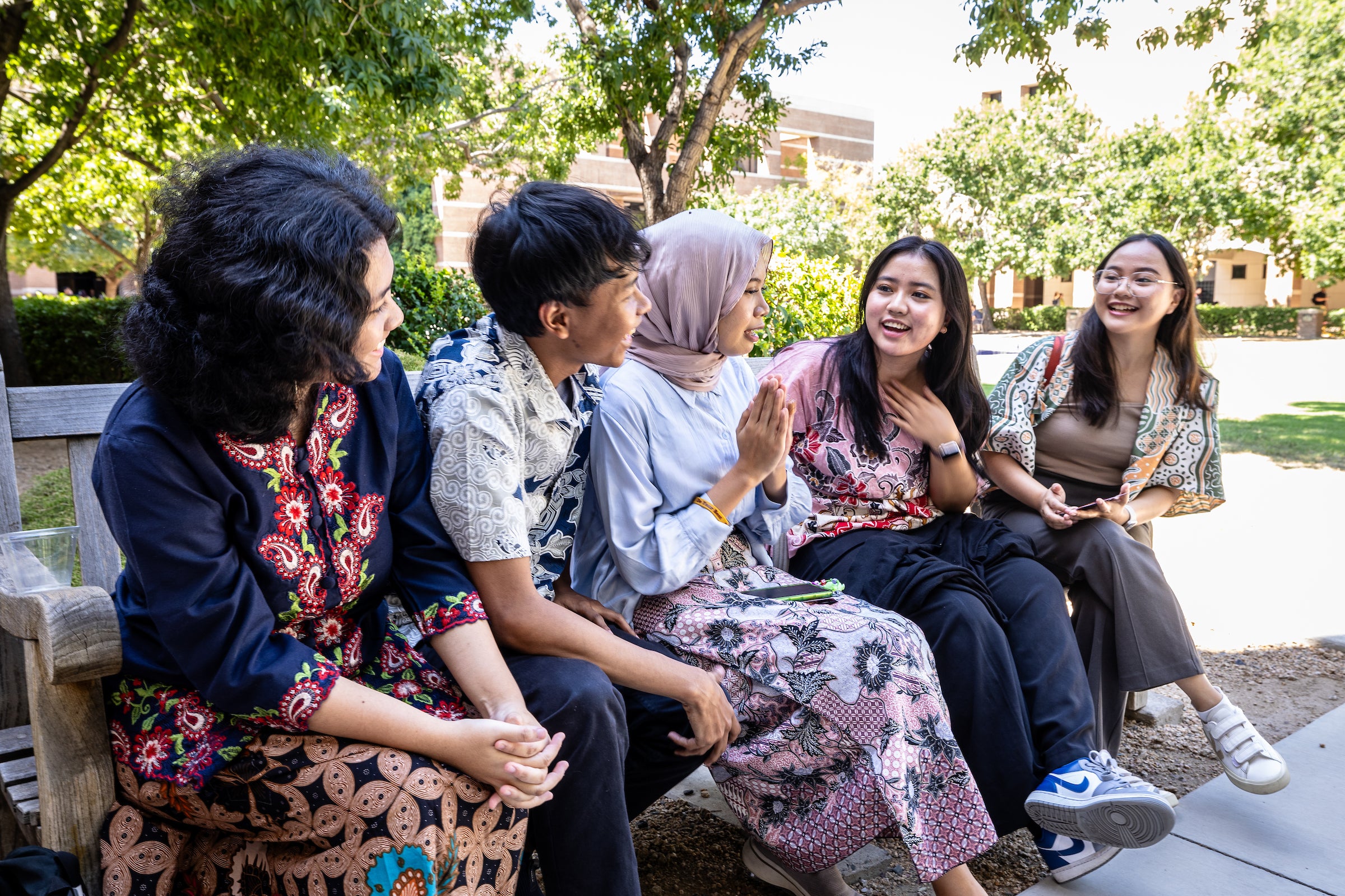 Group of students sit on a bench on ASU's West campus