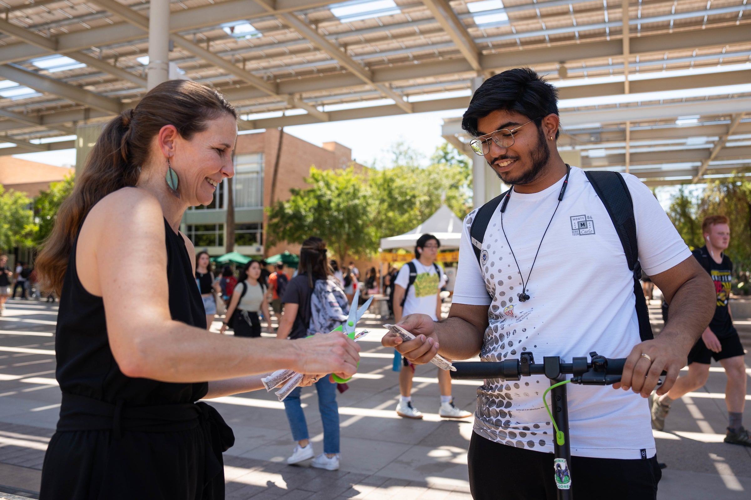 Woman handing out popsicle to student on bike