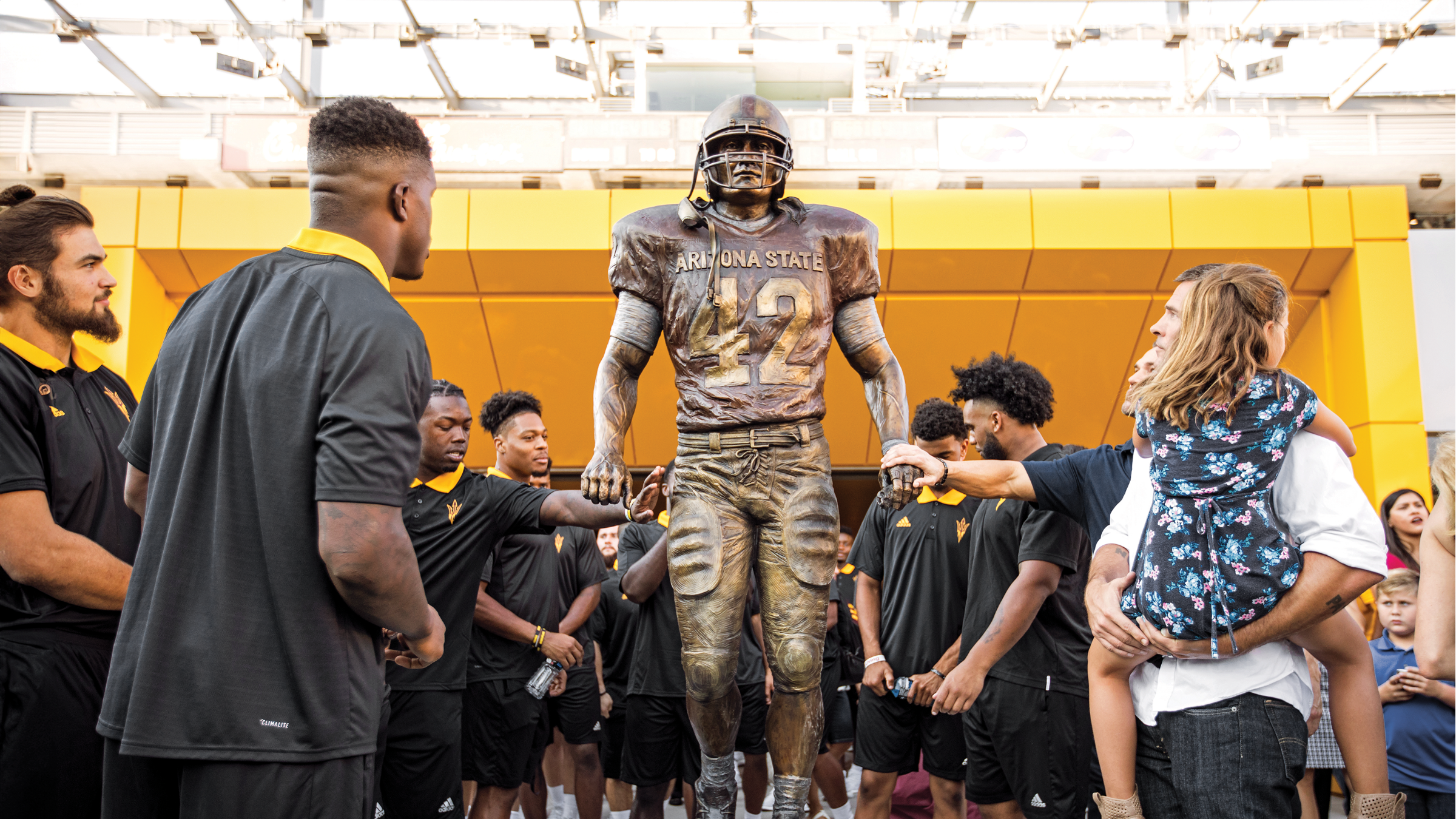 Crowd of football players look at new Pat Tillman statue