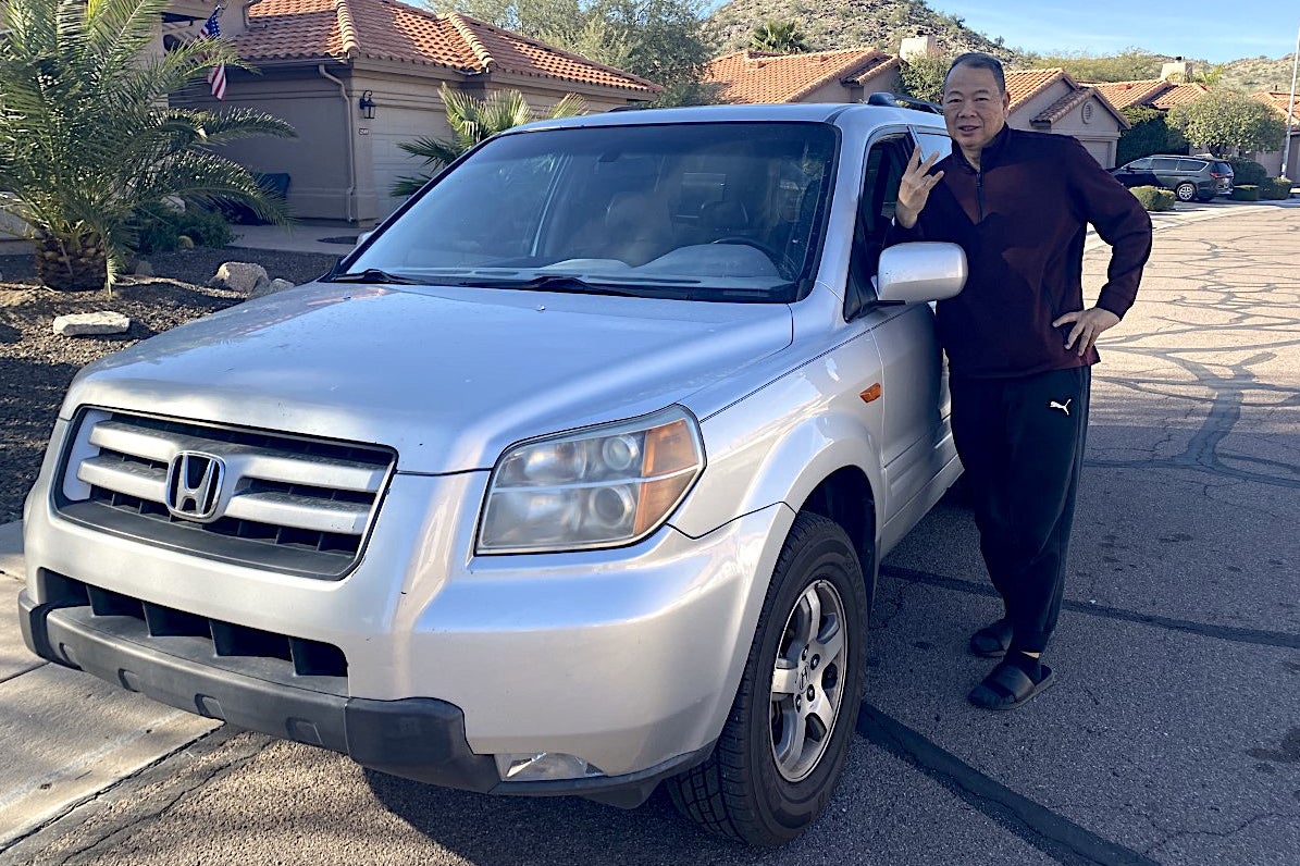 man standing next to Honda Pilot vehicle