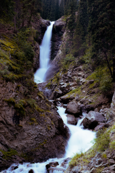 Scenic photo of a waterfall surrounded by green landscape.