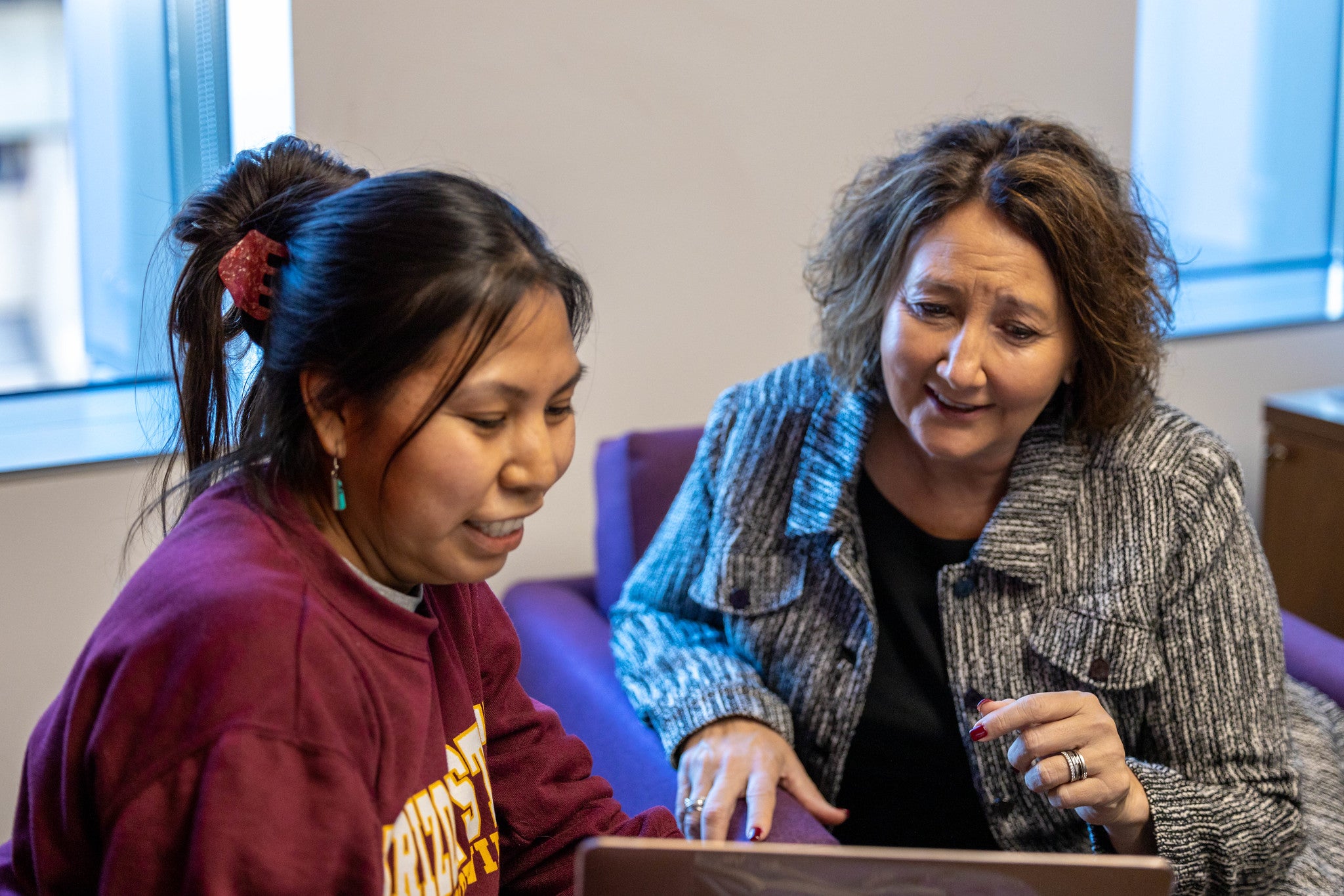 Professor helps student review work on laptop