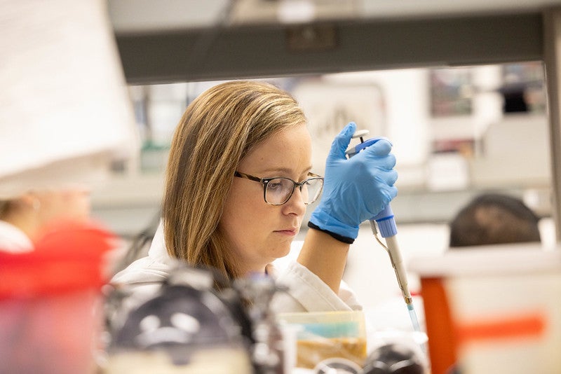 Woman using a pipette in a lab.