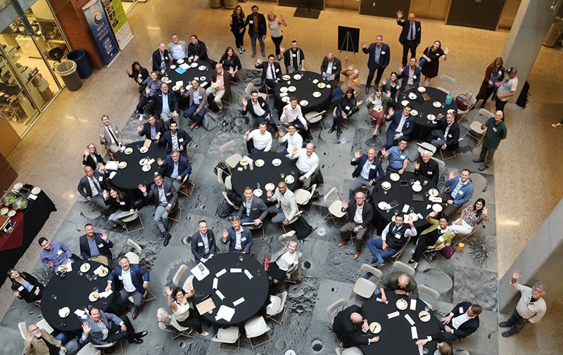  Participants at the Arizona Space Summit wave to an overhead camera from the atrium of AS U’s Interdisciplinary Science and Technology Building IV