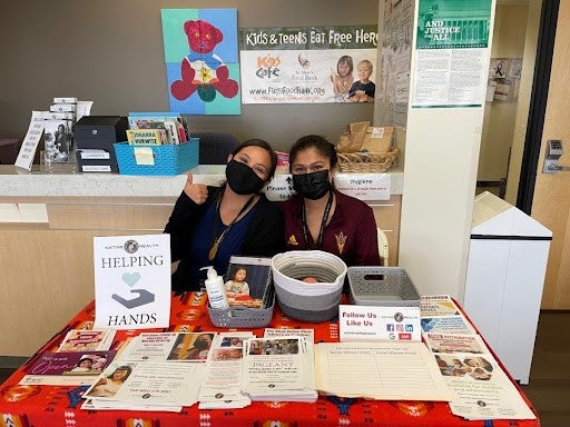 Two women seated behind a table at a health clinic.