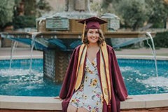 woman in cap and gown sitting on fountain