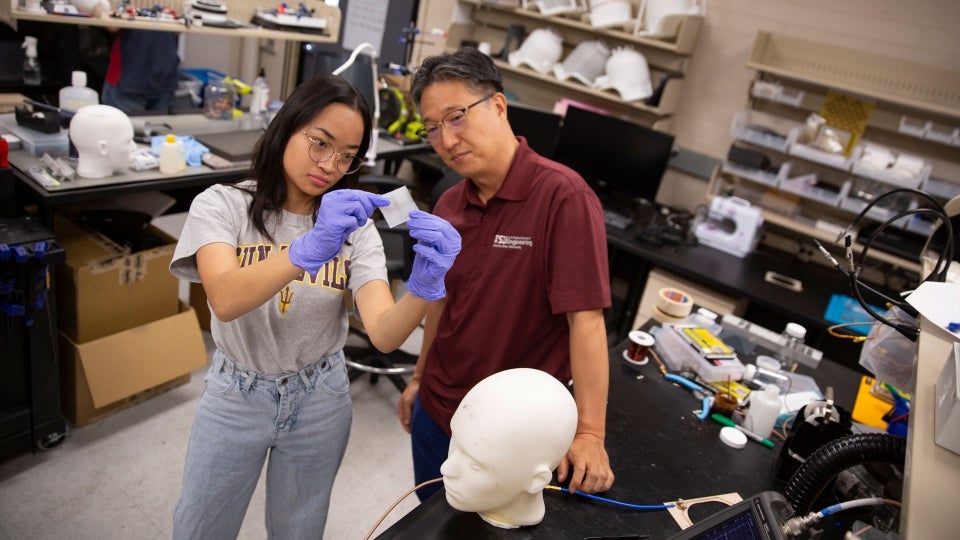 Two people in a lab looking at an item closely.