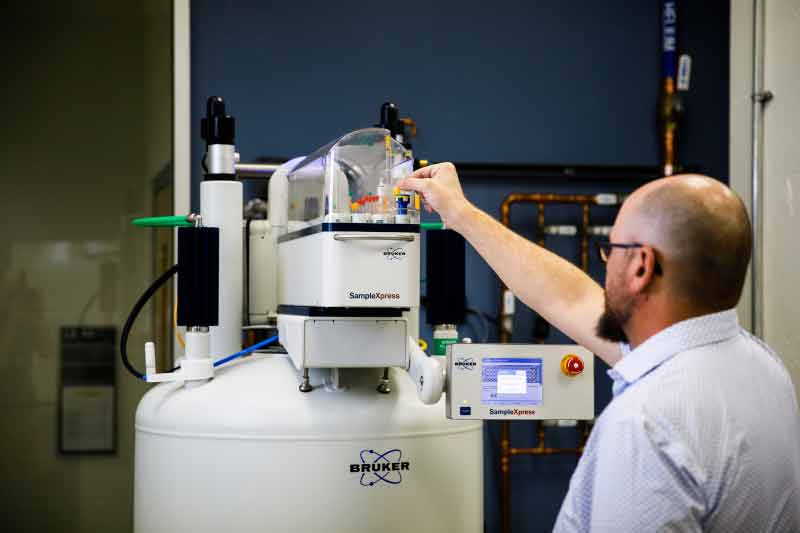 Brian Cherry loads samples into an automated NMR machine for analysis.