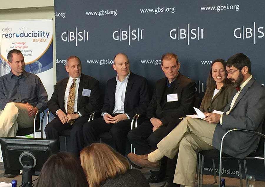 A group of people sit on a stage at a conference.