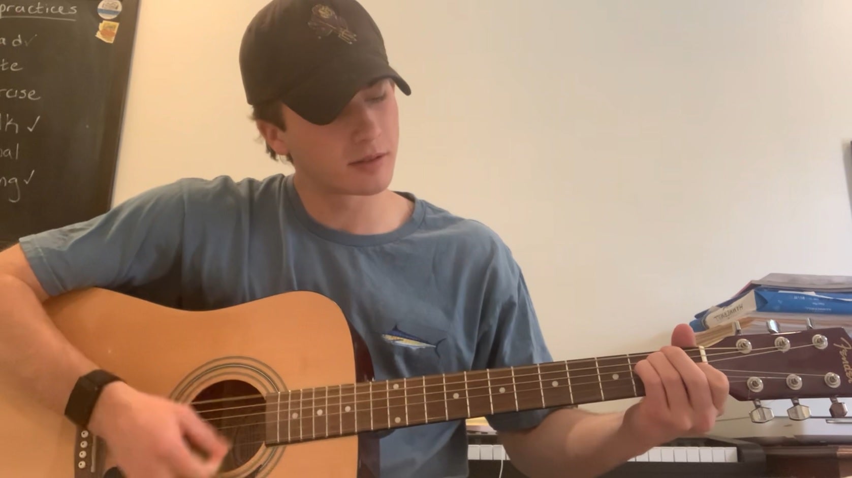 ASU student wearing a hat with Sparky the Sun Devil on it while playing guitar