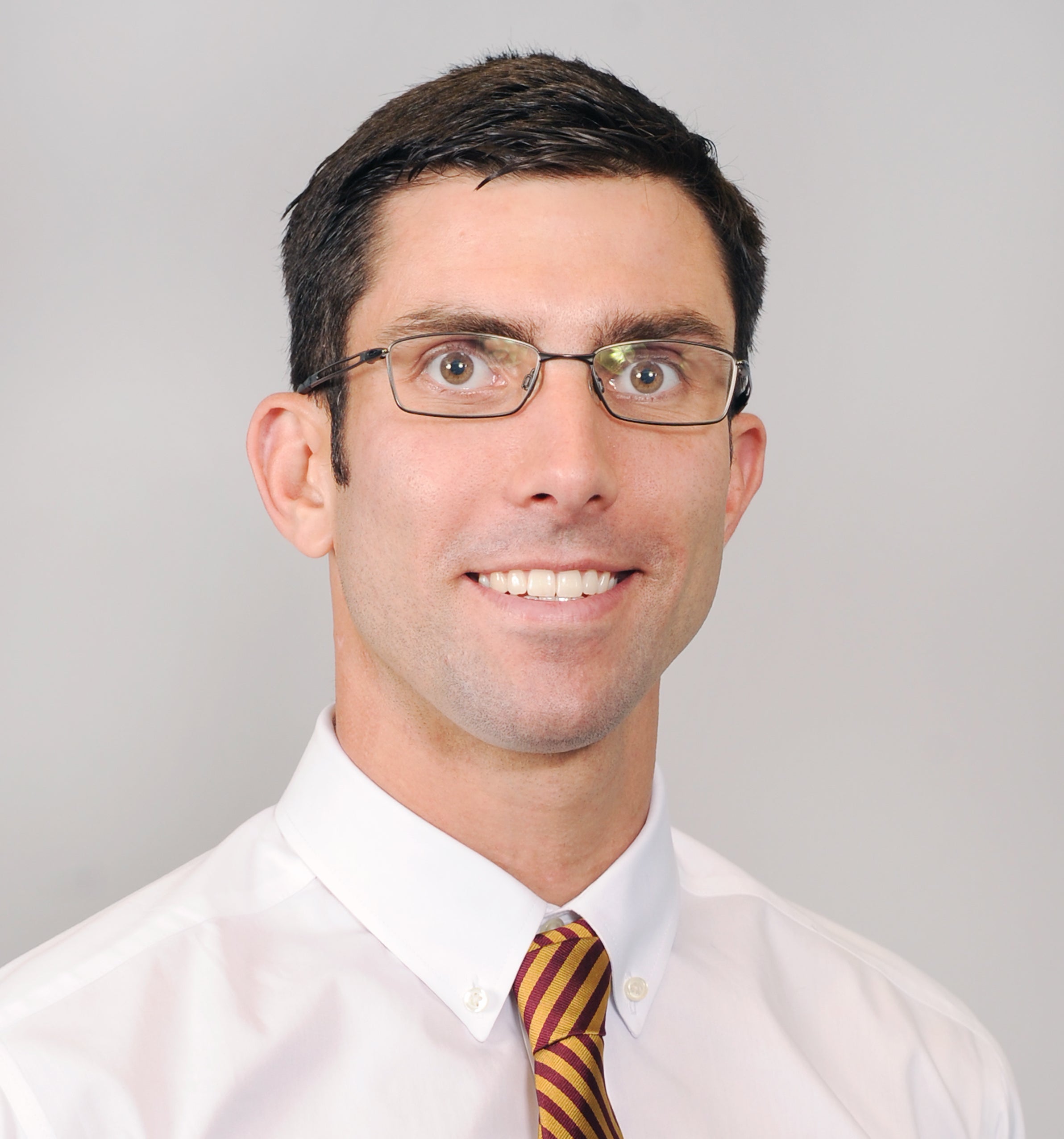 Man in glasses and maroon and gold tie