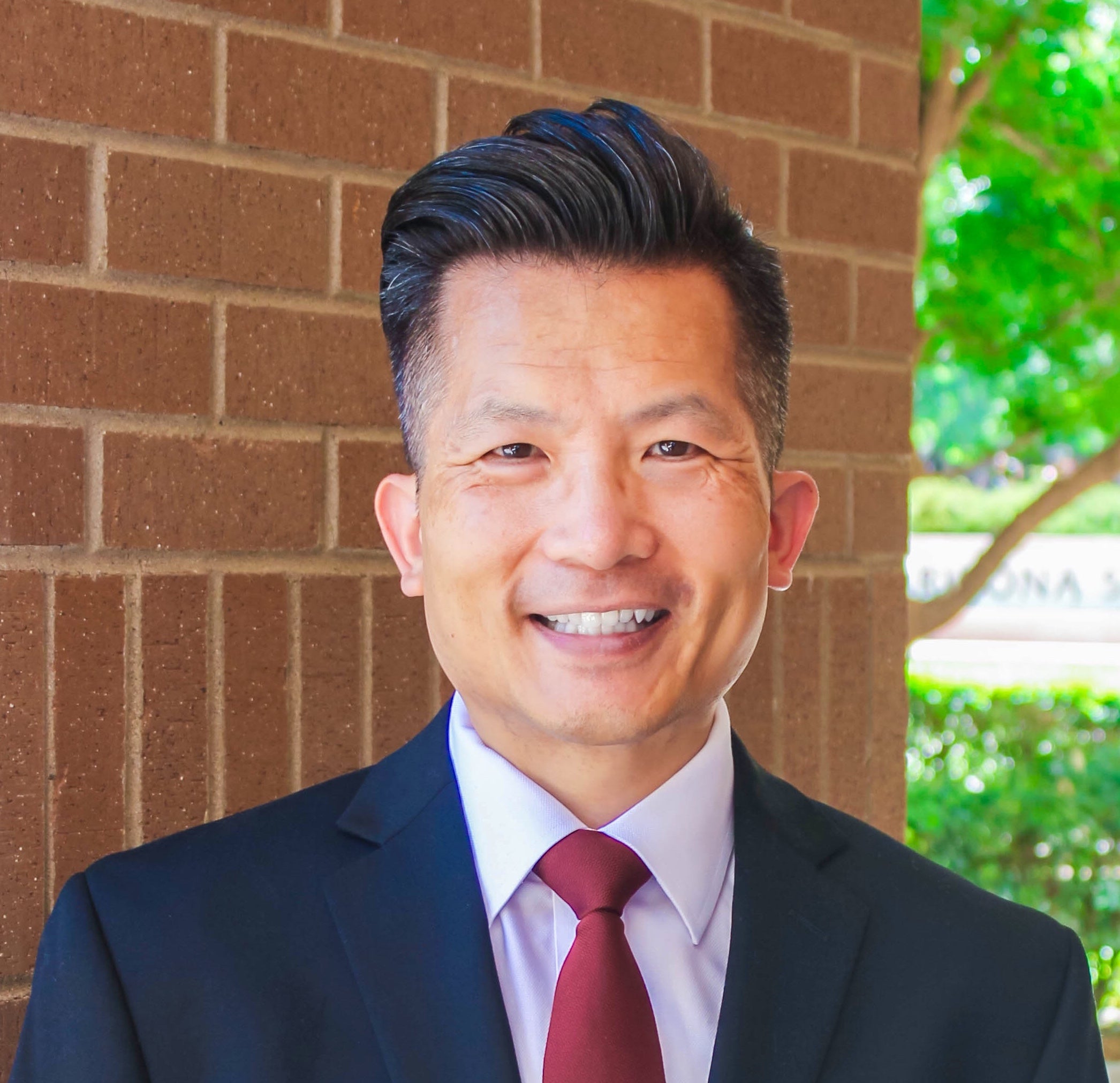 Man with wavy hair in red tie and suit