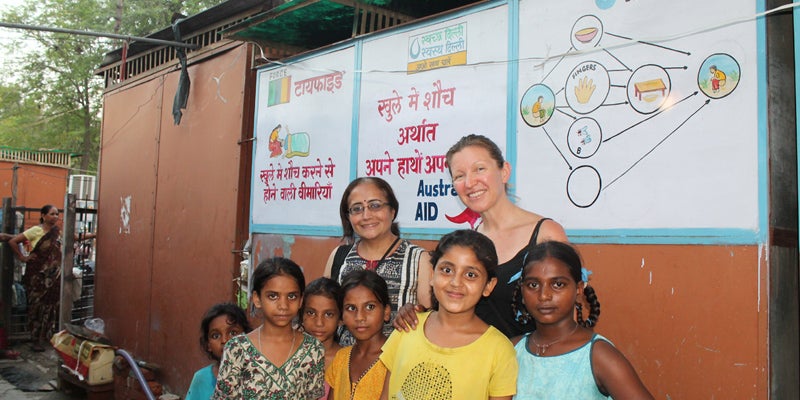 People pose for a photo outside a community toilet in a Delhi slum